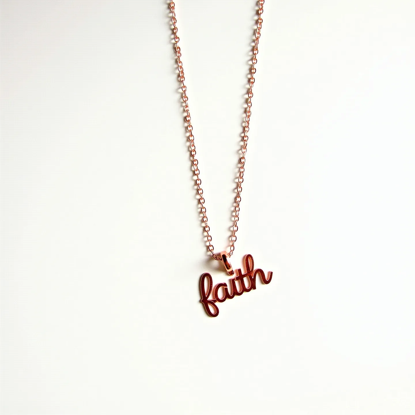 This faith necklace features a delicate chain likely made of rose gold or a similar metal, with a polished finish that adds a subtle shine. The pendant is crafted in a cursive script, spelling out the word "faith," and matches the material of the chain. There are no visible gems or stones in the design, emphasizing simplicity and elegance. The closure is not visible in the image, but it typically would be a standard lobster claw or spring ring clasp to ensure security and ease of wear. Overall, this piece is a minimalist yet meaningful accessory.