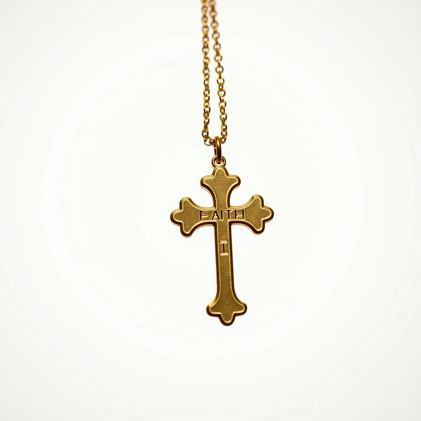 This faith necklace features a cross pendant inscribed with the word "FAITH" crafted from a gold-toned metal, showcasing a smooth and polished finish. The pendant exhibits a rounded, slightly bulbous design at the ends of the cross, adding a touch of elegance. The necklace is suspended from a fine gold-toned chain, likely made of a similar metal, with small, interconnected links that provide a delicate yet sturdy appearance. It is attached securely to the pendant through a loop at the top, facilitating easy movement. The simplicity of the design highlights the inscription as the focal point of the piece.