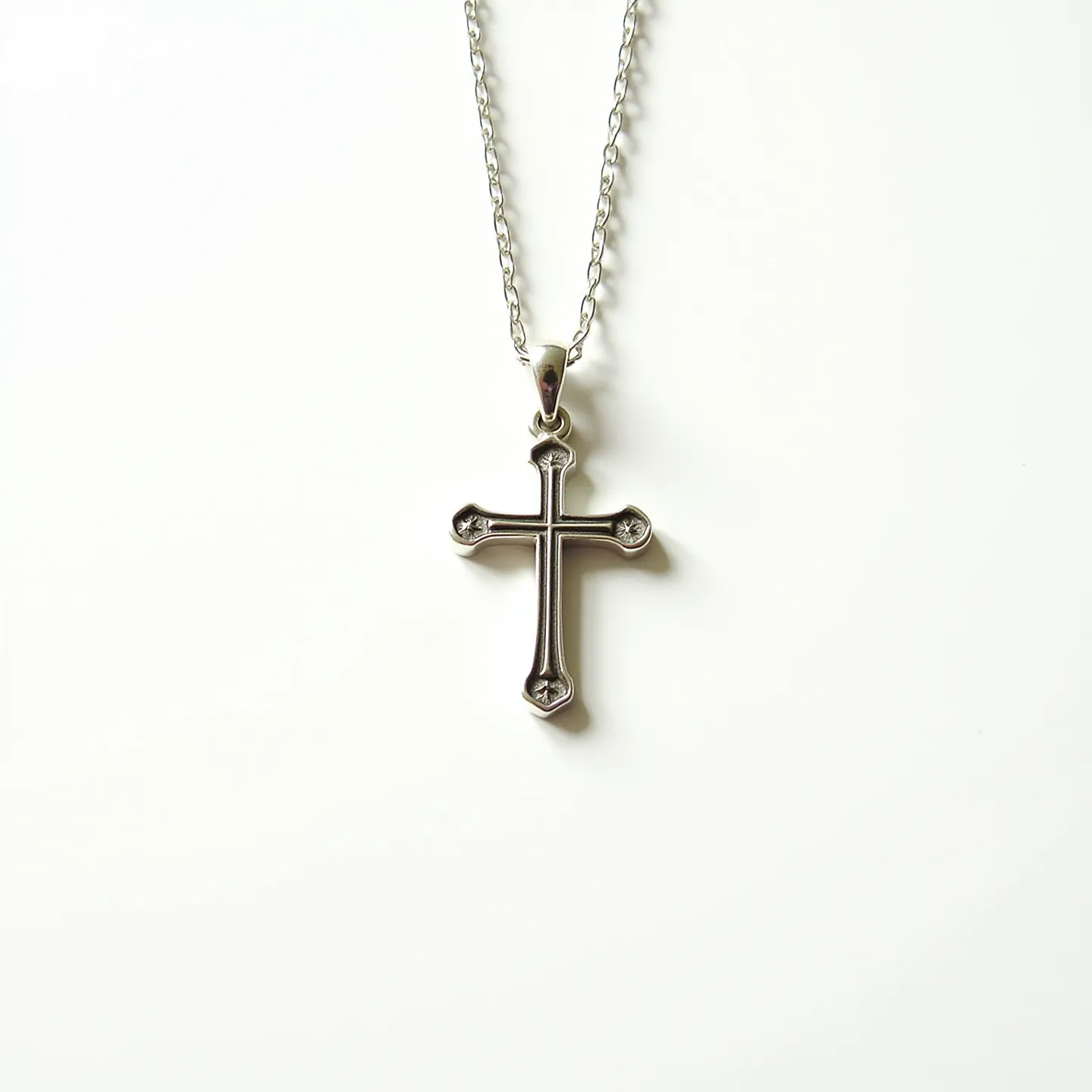 This faith necklace features a sleek metal chain paired with a cross pendant. The cross is designed with a polished silver-tone finish, adding an elegant touch. Each end of the cross is adorned with small, round-cut stones set in the metal, providing a hint of sparkle. The pendant is suspended from the chain via a bail, ensuring it hangs securely. The chain appears to utilize a common lobster clasp for easy attachment and removal, offering both functionality and style.