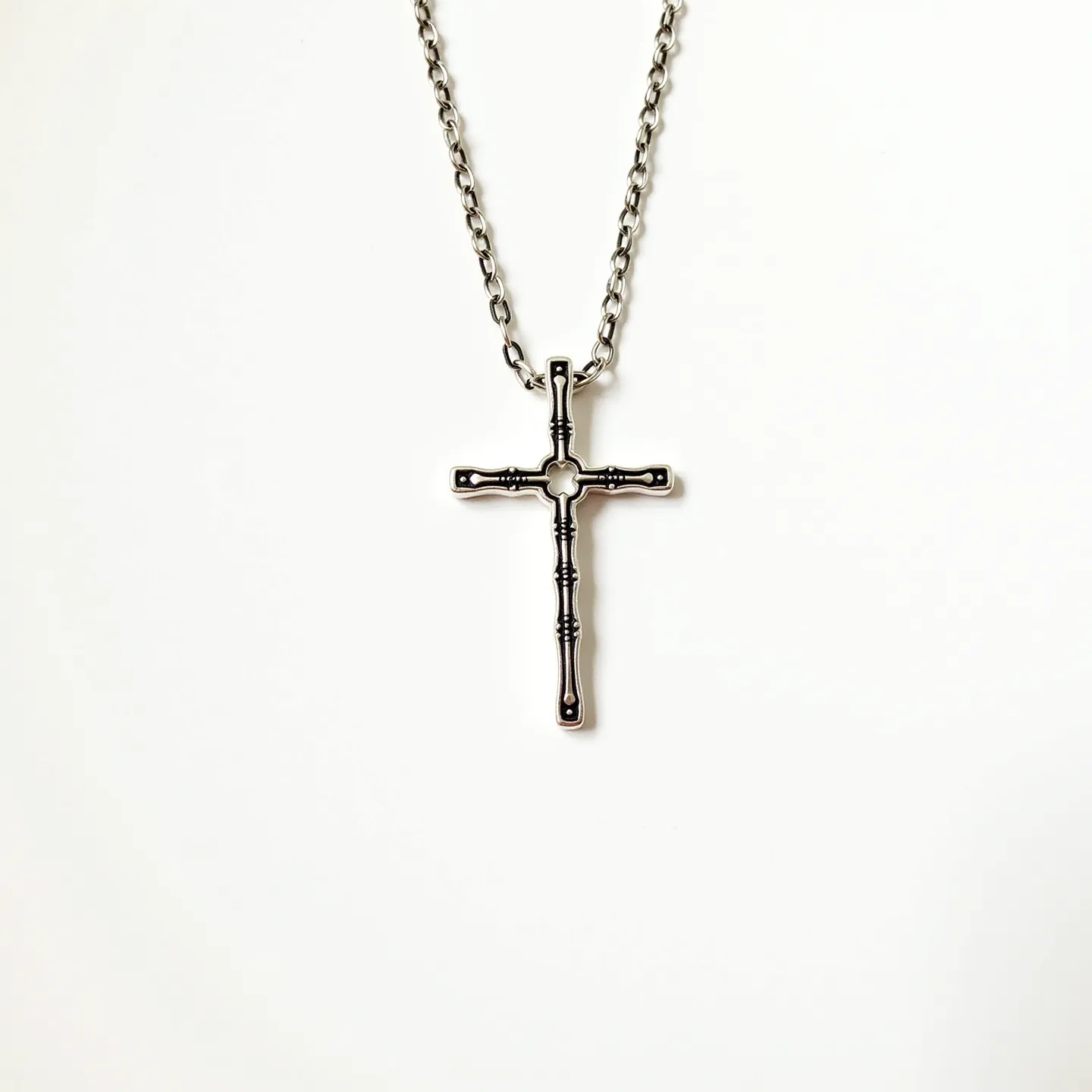 This faith necklace features a cross pendant crafted from metal, designed with a distinctive rod-like texture along both the vertical and horizontal bars. The pendant is suspended from a chain that appears to be made of a similar metal, featuring interlocking links that offer durability and style. The chain secures with a standard lobster clasp, providing ease of wear and a reliable closure. The absence of any visible gemstones or other embellishments highlights the minimalist and elegant design, emphasizing the significance of the cross itself.