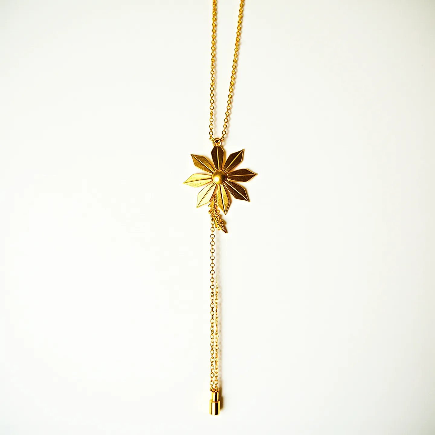 This flower necklace features a central flower pendant crafted from gold-toned metal, with a polished finish that enhances its intricate petal design. The pendant is suspended from a delicate gold chain, which complements the floral motif. The necklace includes a sleek bar and ball chain attachment at the bottom, adding a modern touch to the classic floral design. A slender, cylindrical clasp accents the chain, likely serving as the closure, ensuring the necklace is both secure and stylish. The necklace beautifully combines elegance and nature-inspired artistry.