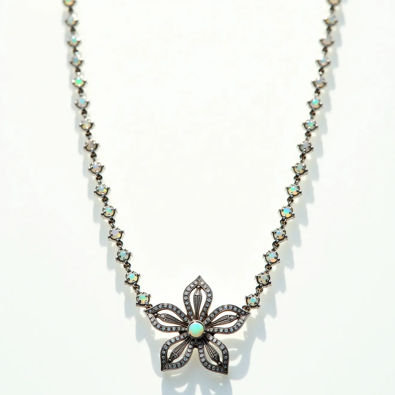 This flower necklace features a delicate chain adorned with small, round opal-like gems, each set in a dainty prong setting that forms an intricate pattern along the length of the necklace. The centerpiece is a floral pendant, showcasing a five-petal design with openwork detailing. Each petal is outlined with what appears to be small diamonds or diamond-like stones set in a pavé setting, adding a subtle sparkle to the piece. At the heart of the flower lies a larger, round opal stone, seamlessly secured with a bezel setting that vividly captures light. The overall design is complemented by a likely metal of gold or silver hue, providing a cohesive and elegant look. The necklace is completed with a clasp or attachment that suggests ease of wear while maintaining the piece's seamless design.