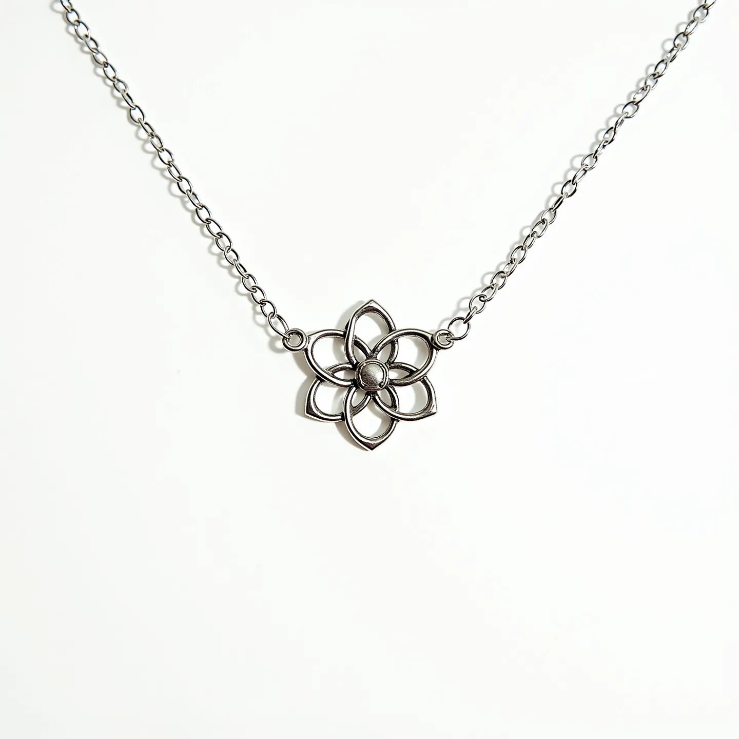 This flower necklace features a delicate and intricate flower pendant crafted from a silver-toned metal, closely resembling a stylized floral motif. The centerpiece of the flower is accented with a small, round central bead, enhancing its design. The pendant is suspended from a fine, matching chain that complements the overall aesthetic. The design suggests simplicity and elegance, with no visible gemstones or additional embellishments. The necklace is likely secured with a standard clasp, ensuring ease of wear.