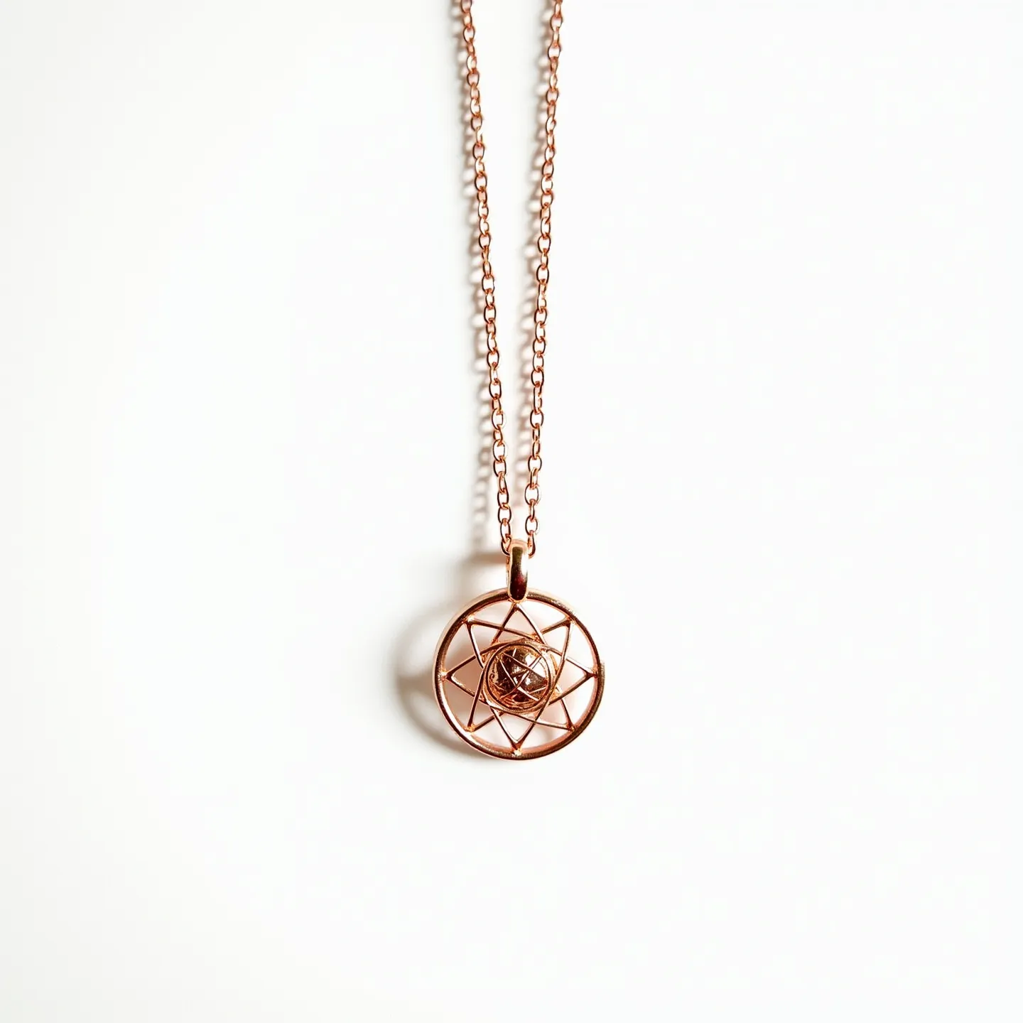 This girl's necklace features a delicate chain made of a rose gold-colored metal, known for its warm and elegant hue. The pendant is a geometric design with a circular frame and an intricate wire pattern that forms overlapping loops, resembling a star. At the center of the pendant is a small, round stone, possibly a gem, set in a bezel setting that securely holds it in place. The necklace is likely fastened with a standard clasp, ensuring it stays securely around the neck. The combination of the metallic sheen and the central stone provides a sophisticated and stylish look.