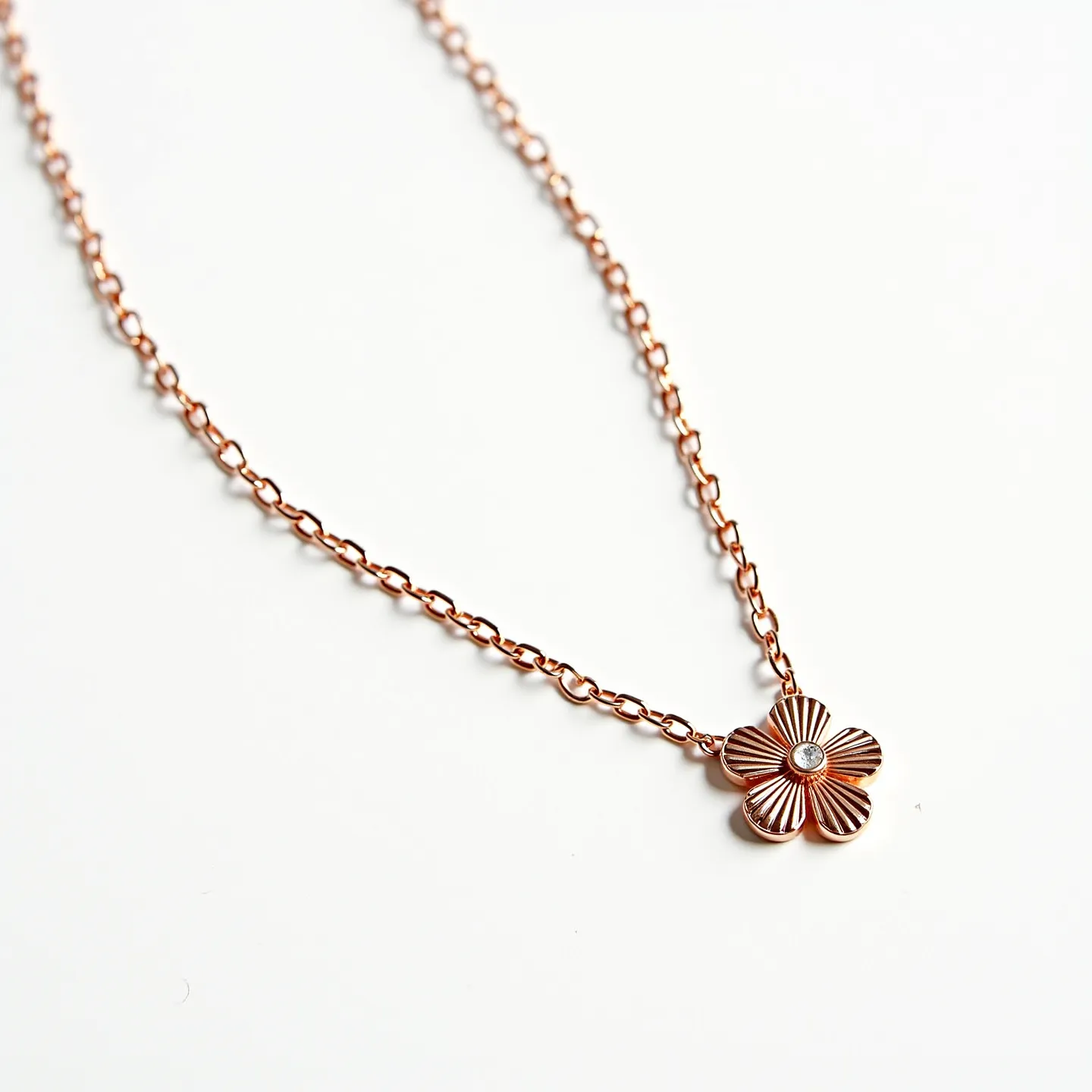 This girl's necklace features a delicate chain made of rose gold, adding a warm and elegant touch. The pendant is designed in a floral shape, with intricately textured petals. At the center of the flower, there is a small, round brilliant-cut gem, likely a diamond, set into the pendant, which enhances its sparkle and allure. The necklace appears to have a standard clasp, ensuring secure wearability. Its overall design combines simplicity with sophistication, making it a versatile accessory for various occasions.