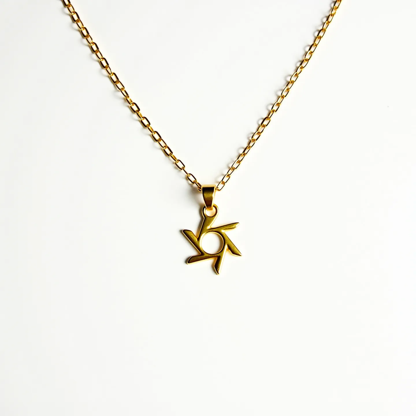 This girl's necklace features a delicate gold chain that supports a modern geometric pendant. The pendant appears to be crafted from the same gold material, with a stylized design that resembles a six-pointed abstract star or flower. The chain links are oval-shaped, giving a classic yet elegant appearance. There are no visible gemstones or additional embellishments on the pendant, keeping the design sleek and minimalistic. The necklace is likely fastened with a simple, small clasp, though it is not prominently visible in the image.