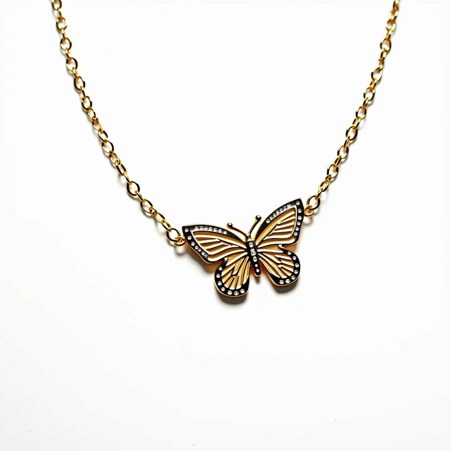 This girl's necklace features a delicate chain likely crafted from a metal with a gold finish. At its center is a butterfly pendant, intricately designed with detailed wings outlined in black, adorned with a series of small, clear stones that resemble gemstones, possibly rhinestones, laid in a bezel setting to enhance their brilliance. The chain links are oval and connected seamlessly, complementing the butterfly's elegant aesthetic. It appears to have a standard clasp attachment, ensuring it is secure when worn.