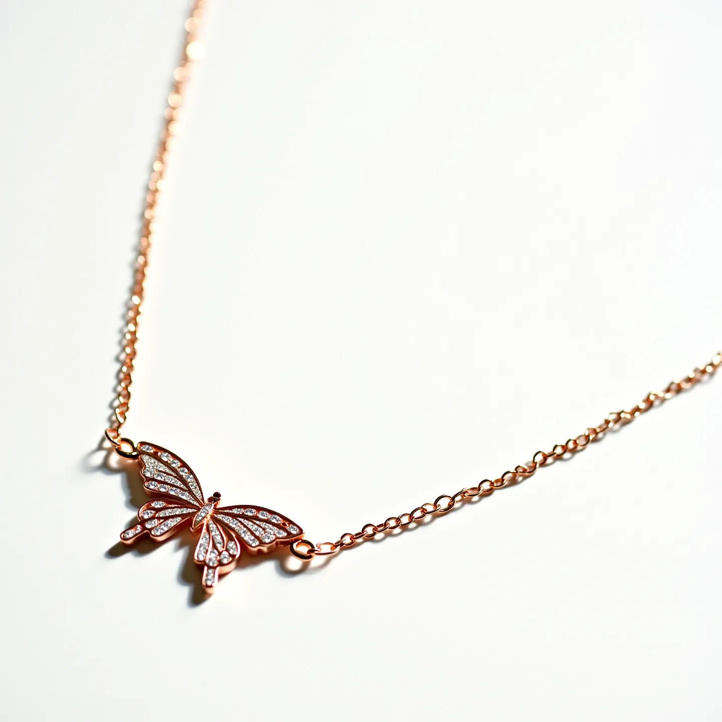 This girl's necklace features a delicate chain with a central butterfly pendant crafted in rose gold. The butterfly is adorned with small, sparkling stones that resemble diamonds, arranged in a pavé setting to enhance their brilliance. The stones are neatly embedded within the wings, following their contour for a cohesive look. The necklace likely has a subtle clasp at the back, though it isn't visible here, which would typically be a spring ring or lobster clasp to secure the piece. The combination of rose gold and shimmering stones gives the necklace an elegant and youthful appearance.