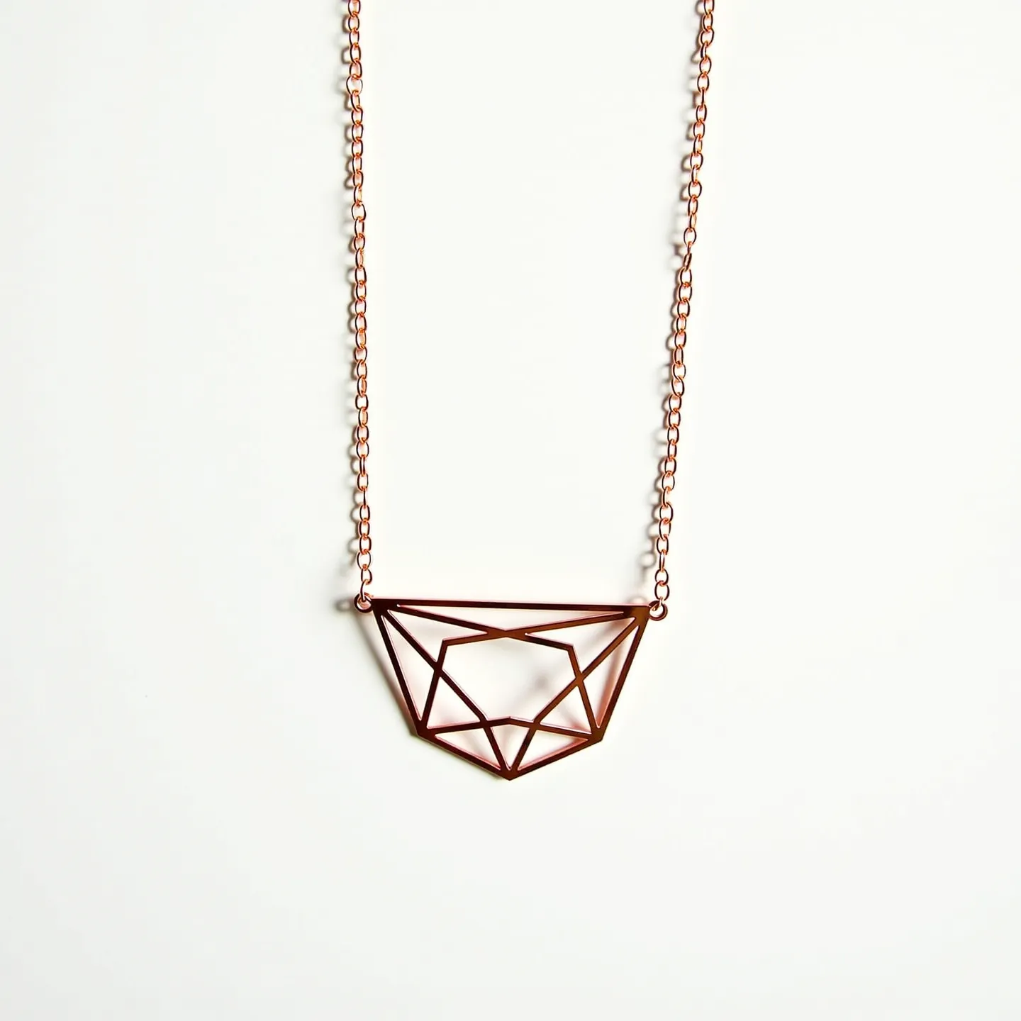 This girl's necklace features a geometric pendant made of metal with a warm copper tone, forming an abstract, angular shape reminiscent of cut gemstones. The pendant is delicately suspended from a chain composed of small, evenly sized links that complement the design's simplicity and elegance. The overall structure suggests a clean, modern aesthetic. The pendant hangs from two small loops attached to either side, integrating seamlessly with the chain. There is no visible clasp shown, which could indicate a continuous chain or an attachment at the back not captured in the image.