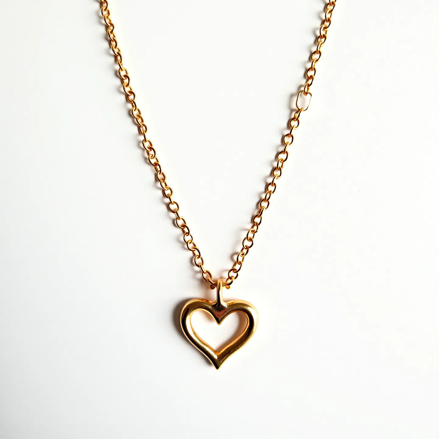 This girl's necklace features a delicate golden chain composed of interlocking round links, giving it a classic yet elegant appearance. The chain elegantly suspends a heart-shaped pendant made from the same gold-tone material, adding a touch of romance and charm. The pendant is polished, providing a shiny and reflective surface. The necklace is likely secured with a classic lobster clasp, ensuring ease of use and durability. The combination of chain and pendant in matching golden hues creates a coordinated and stylish accessory.