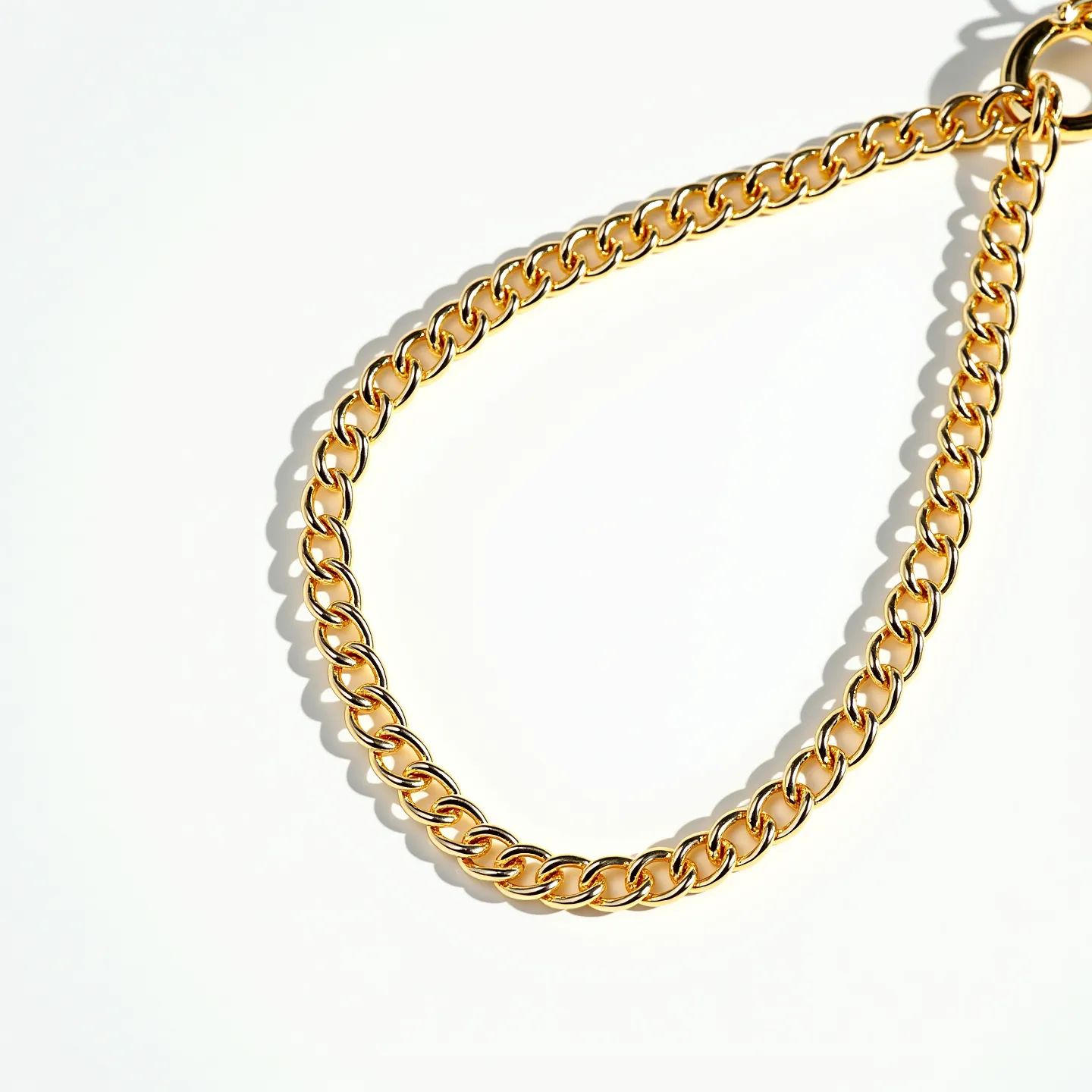 This gold chain features a series of interlocking links displaying a classic curb chain design, which is known for its flat, uniform, and closely connected structure. The metal has a polished finish, enhancing the reflective quality typical of gold jewelry. The chain is unadorned by any additional gems or stones, maintaining a sleek and minimalist aesthetic. It is fitted with an over-sized ring clasp that matches the chain, offering both functionality and a stylish element. The overall appearance is elegant and versatile, suitable for both casual and formal wear.