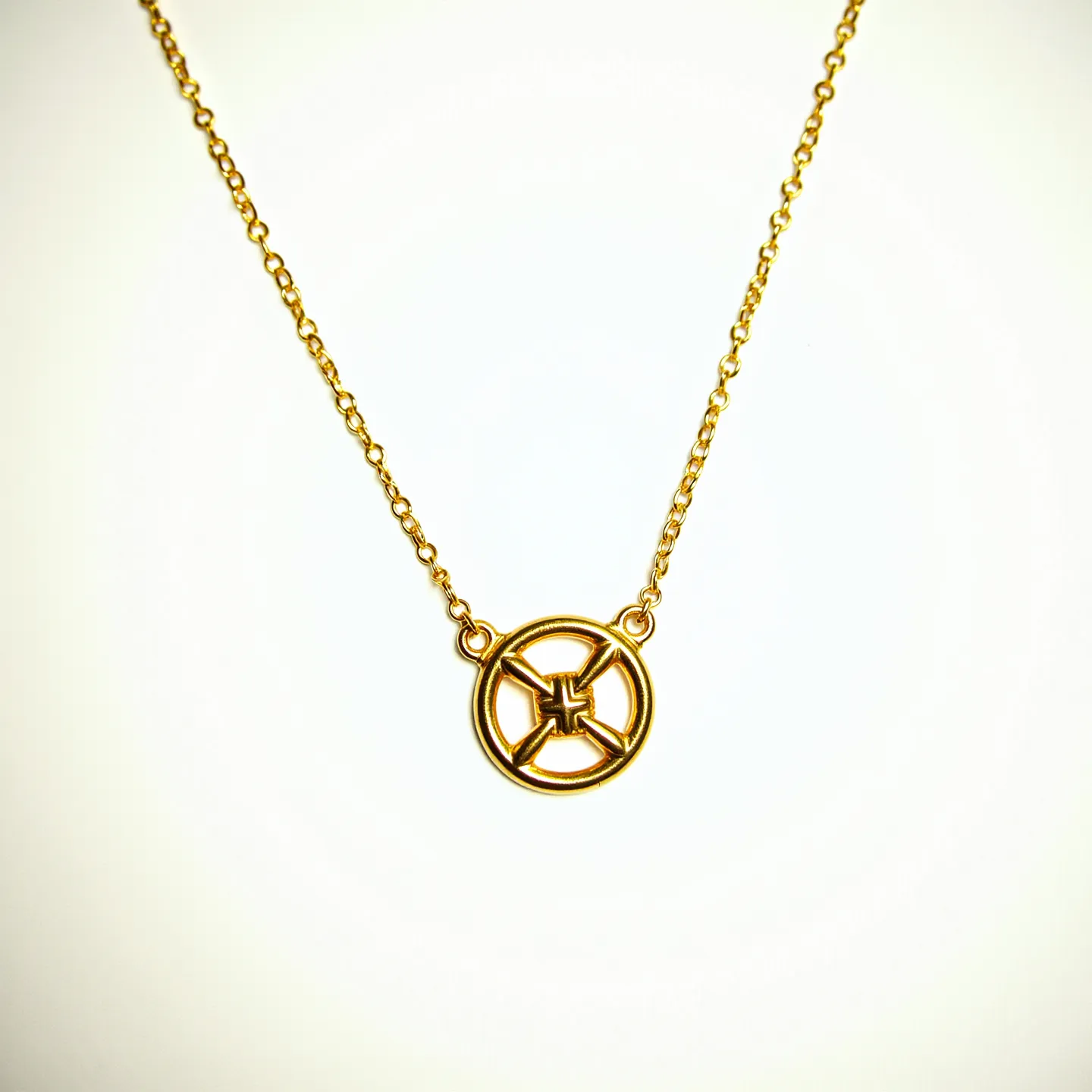 This gold chain features a simple link design, showcasing a round pendant with an intricate symbolic motif in the center. The pendant, made from the same gold material as the chain, is highlighted by its geometric pattern, emphasizing its artistic design. The gold chain connects smoothly to the pendant with small loops on either side, allowing it to hang elegantly. The clasp or attachment appears to be a subtle hook type, ensuring a secure fit around the neck while maintaining the chain's overall aesthetic appeal.