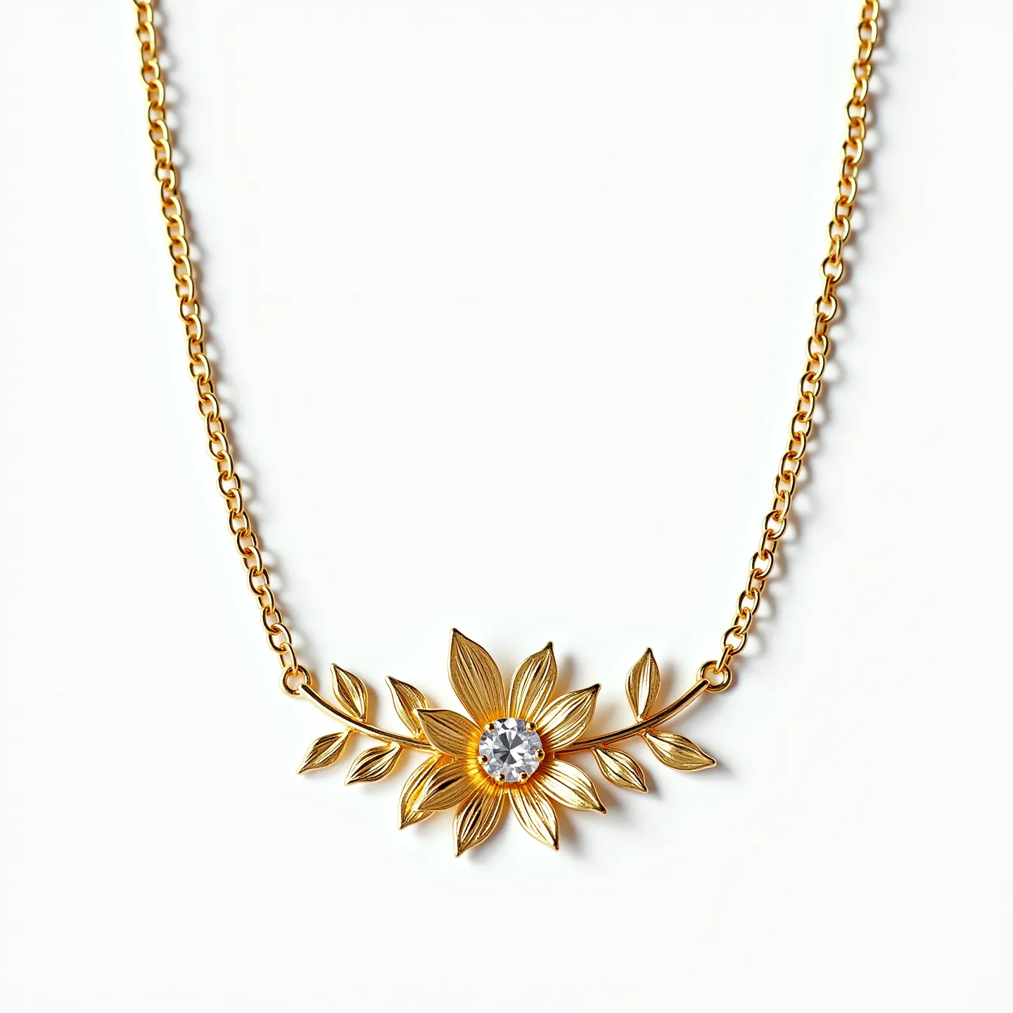 This gold chain necklace features a delicate floral and leaf design as its central element. The centerpiece is a flower crafted from gold, with intricately detailed petals. At the center of the flower is a round, sparkling gemstone, likely a diamond or similar cut stone, set in a secure prong setting that highlights its brilliance. The chain itself is composed of small, tightly linked gold loops, providing a sturdy yet elegant appearance. The necklace likely includes a standard clasp mechanism, though it is not visible in the image.