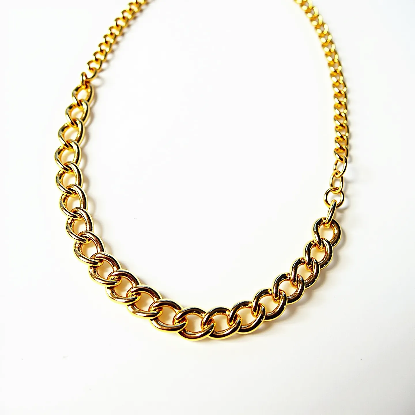 This gold chain necklace features a curb link design characterized by interlocking flat, oval loops that create a sophisticated and elegant pattern. The links are crafted from gold, giving the necklace a lustrous and luxurious appearance. The piece is finished with a simple hook clasp, ensuring security while maintaining the sleek design. The chain’s uniformity and shine make it a timeless accessory suitable for a variety of occasions.