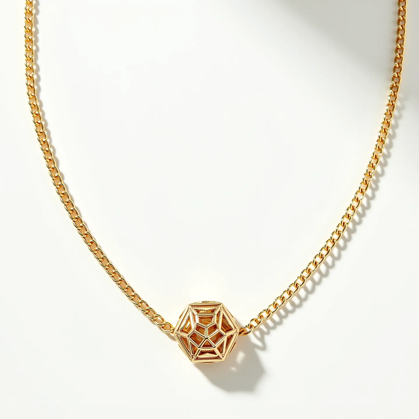 This gold chain necklace features a delicate and elegant design, crafted from polished gold links that come together to form a smooth, flowing chain. At the center is a geometric pendant with a dodecahedron shape, showcasing intricate gold webs that create an openwork effect. The pendant is hollow, allowing light to pass through its structure, highlighting the craftsmanship of the piece. The chain likely includes a standard clasp, providing secure fastening and completing the sophisticated design of this wearable art piece.