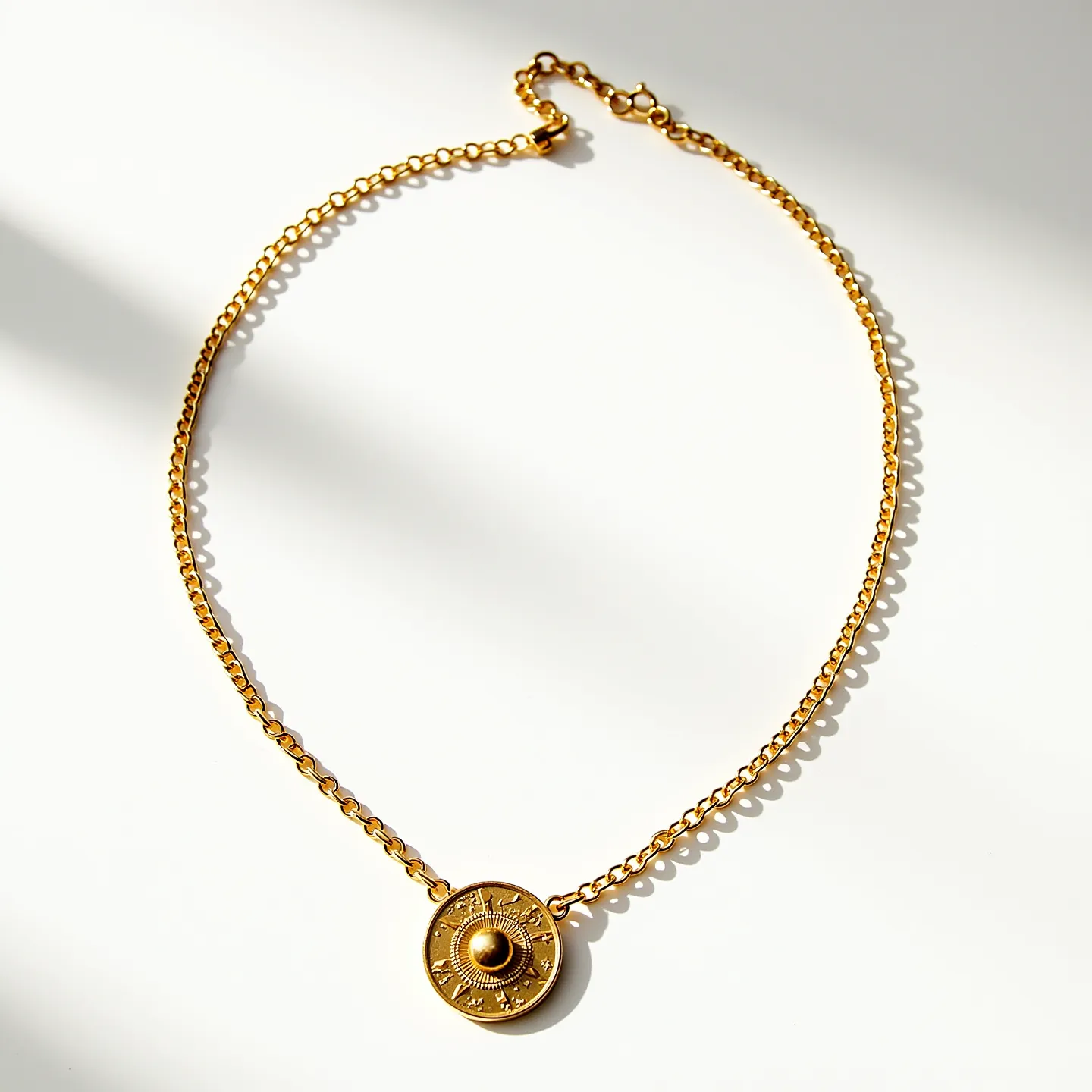 This gold chain necklace features a polished, linked design crafted from metal with a rich golden hue. Its centerpiece is a circular pendant, intricately engraved with a sunburst motif radiating from a central raised dome, adding a touch of elegance and symbolism. The pendant's detailed surface catches the light, enhancing its visual appeal. Secured with a lobster clasp, the necklace ensures a reliable and easy fastening mechanism, making it both stylish and functional.