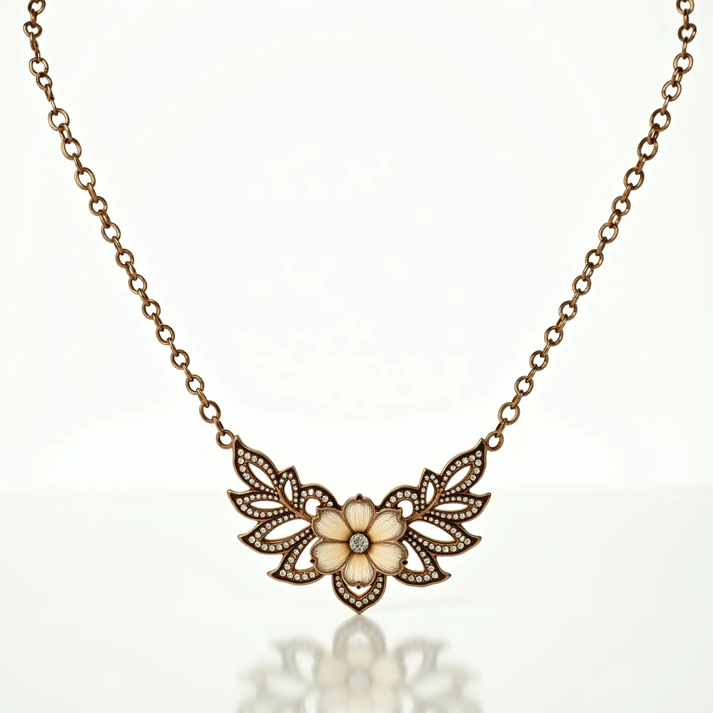 This gold chain necklace features an intricate floral pendant crafted from gold-tone metal. At the center of the flower is a small, round diamond or diamond-like gem in a simple prong setting, providing a subtle sparkle. The flower is flanked by leaf-like extensions, each delicately detailed and possibly accented with small crystals or stones that follow the contours, enhancing the decorative design. The chain consists of uniform round links, complementing the ornate style of the pendant. The necklace includes a standard clasp for secure attachment.