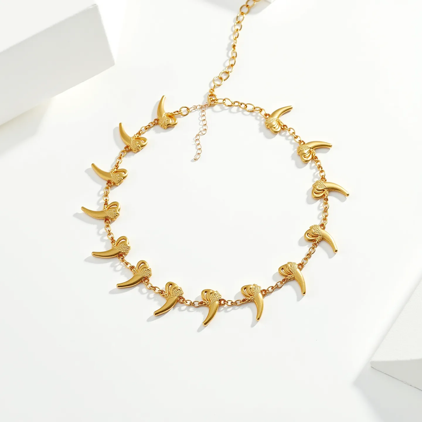 This gold choker necklace features a series of gold charms shaped like claws or elongated talons evenly distributed along a fine gold chain. Each charm appears to be crafted from polished metal that gives off a bright, lustrous shine. The necklace includes an adjustable chain extending from the closure, ending in small links for size customization, and it secures with a typical lobster clasp for both security and ease of use. The design of the necklace is edgy yet elegant, making it a versatile accessory for various occasions.