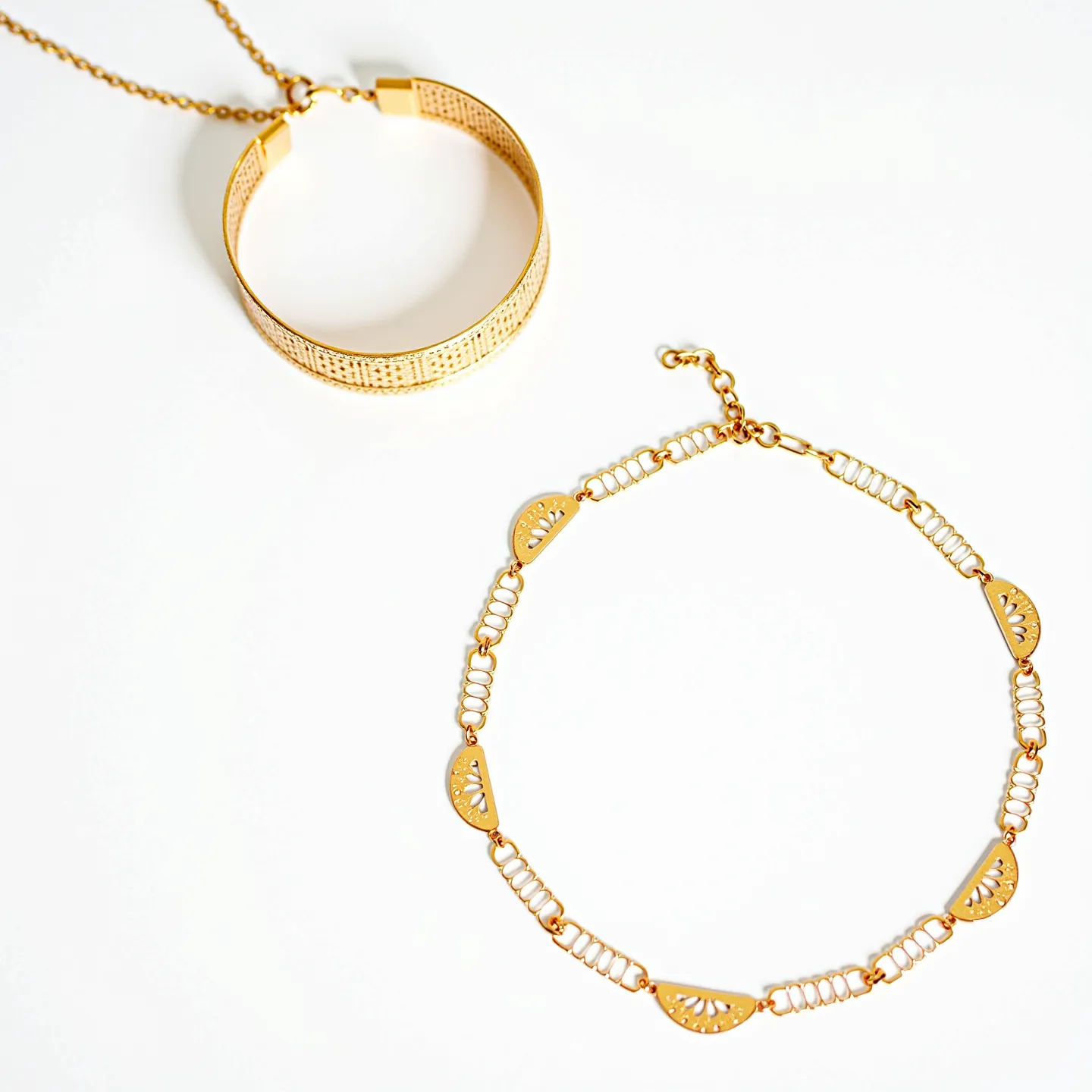 This gold choker necklace features a delicate design characterized by alternating openwork links and semi-circular metal elements. The links showcase intricate cut-out patterns that add an elegant flair to the overall appearance. The necklace is crafted from gold-toned metal, offering a luxurious sheen. It is equipped with an adjustable chain and a secure clasp that allows for customization of fit and ease of wear.