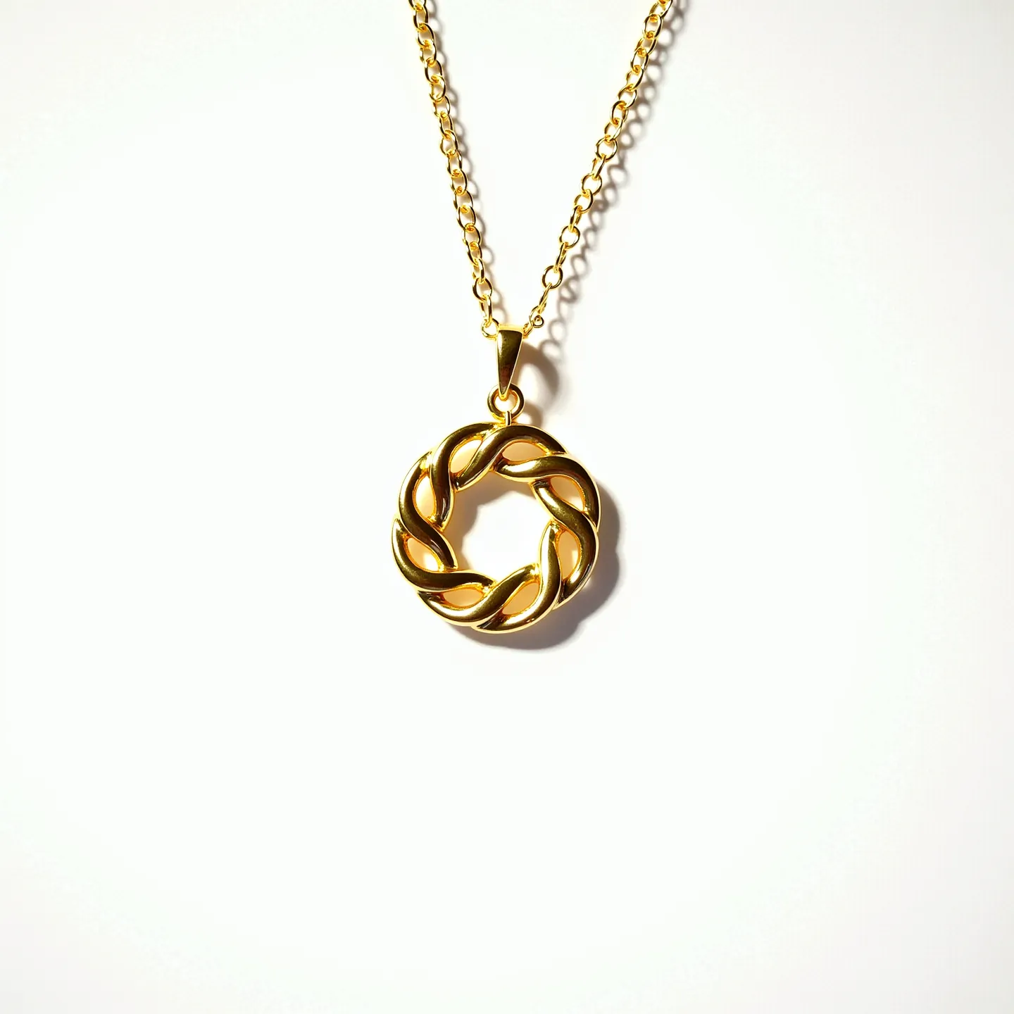 This gold circle necklace features a polished, intertwined design crafted from gold-toned material. The pendant is suspended gracefully from a fine gold chain, contributing to its elegant appearance. The pendant's circular shape is achieved through an intricate weave, giving the piece a sophisticated and timeless look. This necklace is fitted with a sturdy lobster clasp for secure fastening, ensuring ease of wear while maintaining its aesthetic appeal.