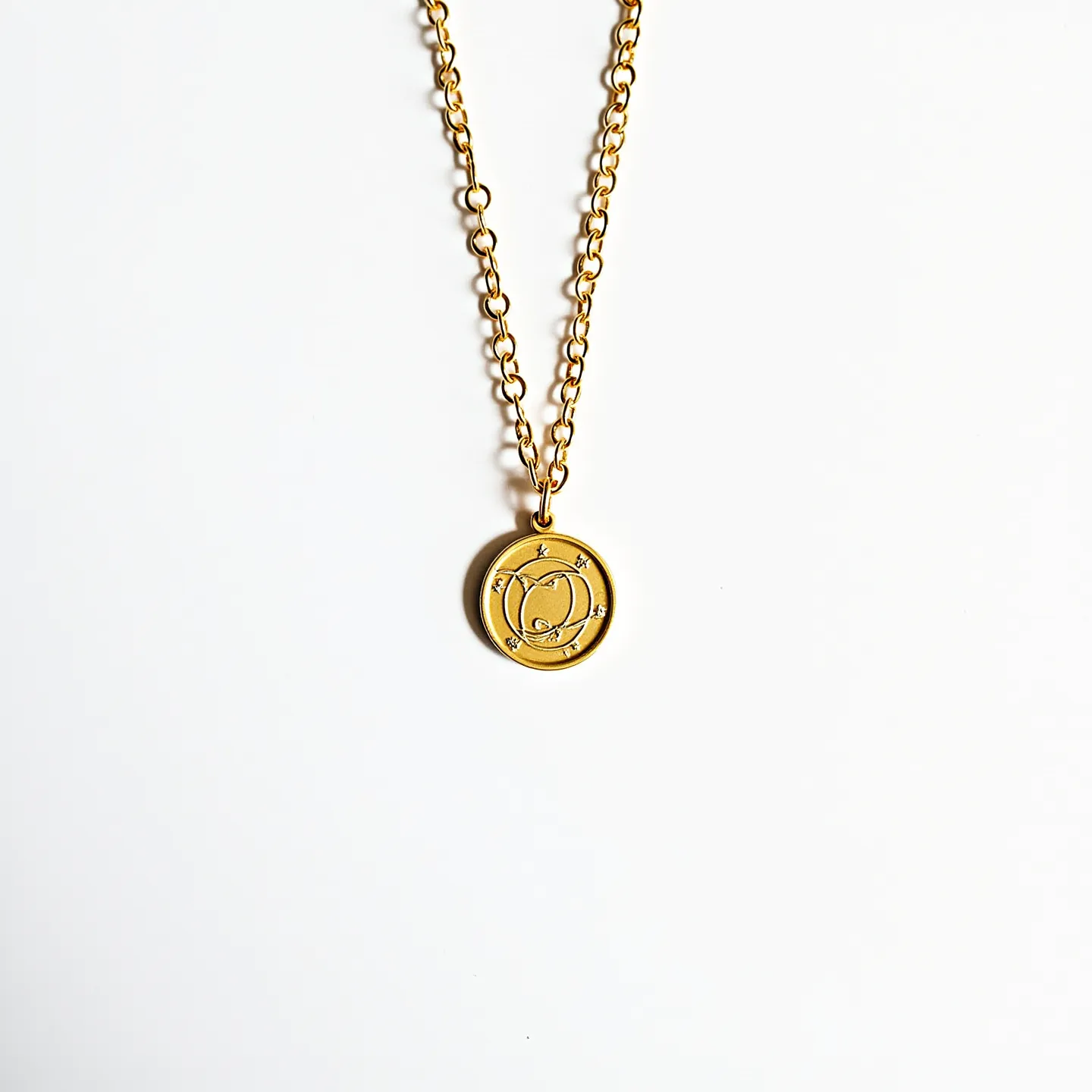 This gold circle necklace features a pendant with an intricate design that includes symbols and possibly astrological or geometric patterns. The pendant is crafted from a polished gold material, giving it a lustrous and elegant appearance. Embedded within the design are several small, sparkling gems that add a touch of brilliance and contrast against the matte gold finish. The chain, consisting of interlocking loops, is made from the same gold material, ensuring continuity in color and style. The necklace is likely secured with a standard clasp, providing ease of wear and security.