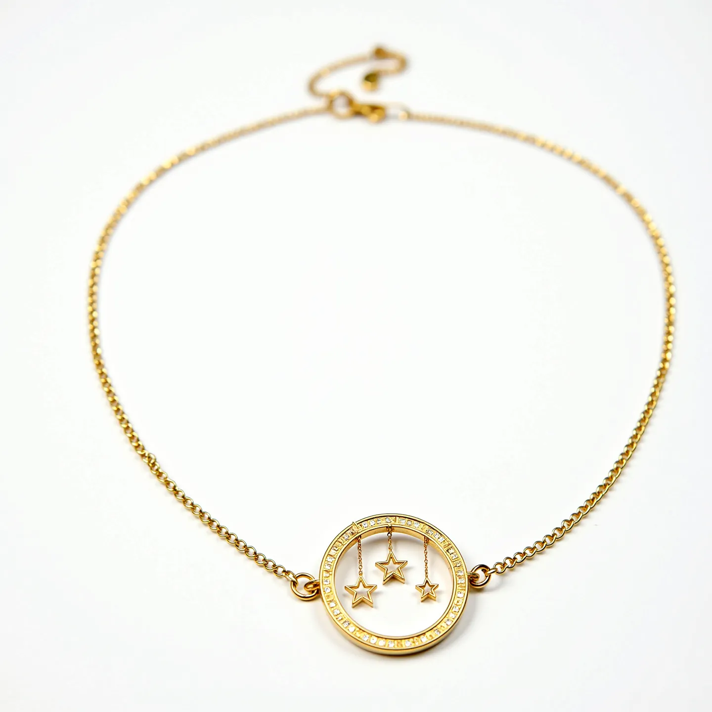 This gold circle necklace features a delicate gold chain connected to a circular pendant. The pendant is adorned with small, evenly spaced stones, possibly diamonds, set in a pave style around its perimeter. Inside the circle, three small gold star charms dangle, each attached by individual thin gold chains, creating a playful and elegant look. The necklace likely has a standard lobster clasp for secure fastening, ensuring ease of wear while maintaining its refined design.