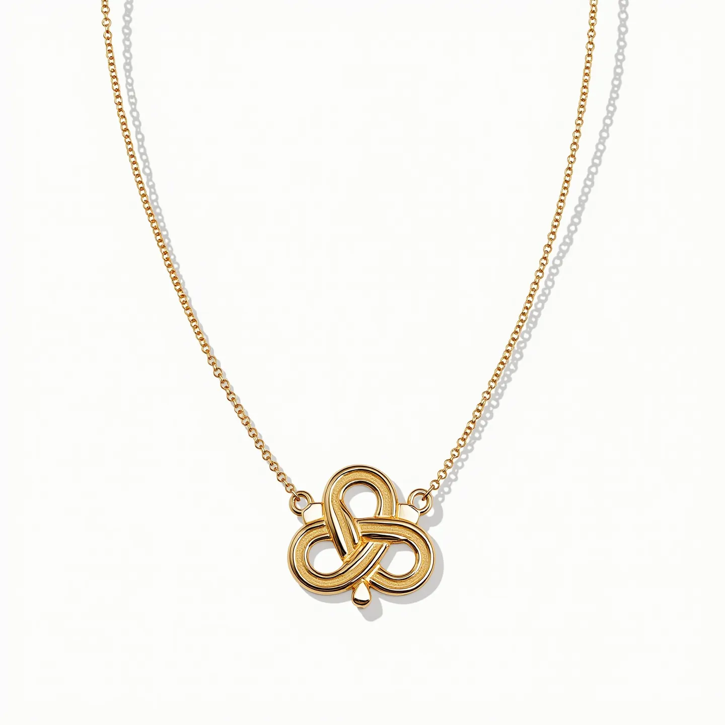 This gold circle necklace features a delicate chain that supports a central pendant with intricate, interlocking loops forming a symmetrical clover-like design. The material appears to be polished gold, lending a glossy and elegant finish. The necklace chain links are finely crafted, suggesting durability and a refined aesthetic. The design does not include any visible gems or stones, focusing instead on the elegant simplicity and the craftsmanship of the gold shapes. The attachment seems to be a classic style that complements the overall minimalist yet sophisticated look of the piece.