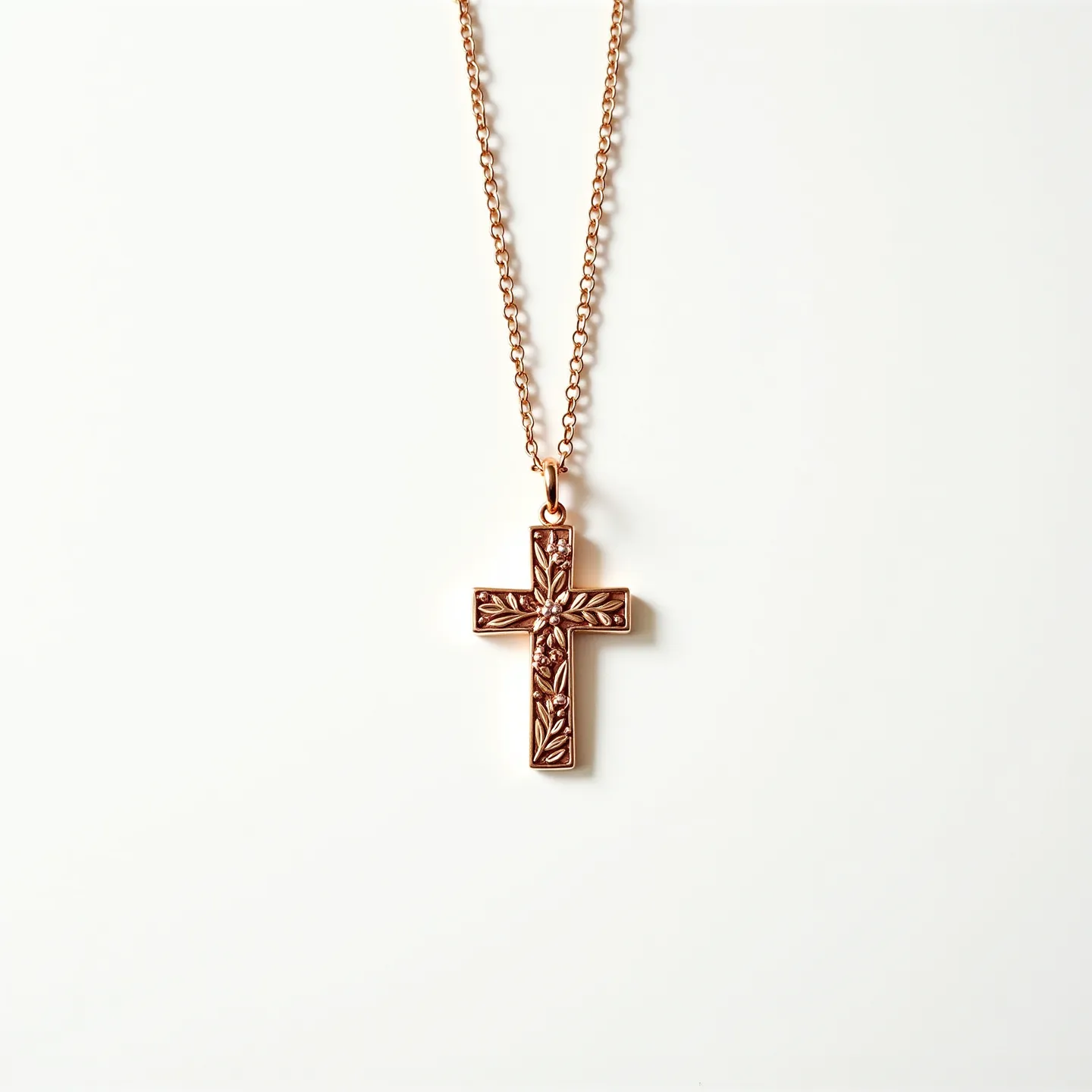 This gold cross necklace features an intricately designed pendant crafted from gold, showcasing delicate floral engravings that add a touch of elegance and intricacy to the piece. The cross is simple yet artistic, reflecting light beautifully across its textured surface. It hangs from a gold chain characterized by small, uniform links that provide both durability and a refined appearance. The attachment between the cross and the chain is a classic bail, ensuring smooth movement and a secure connection.