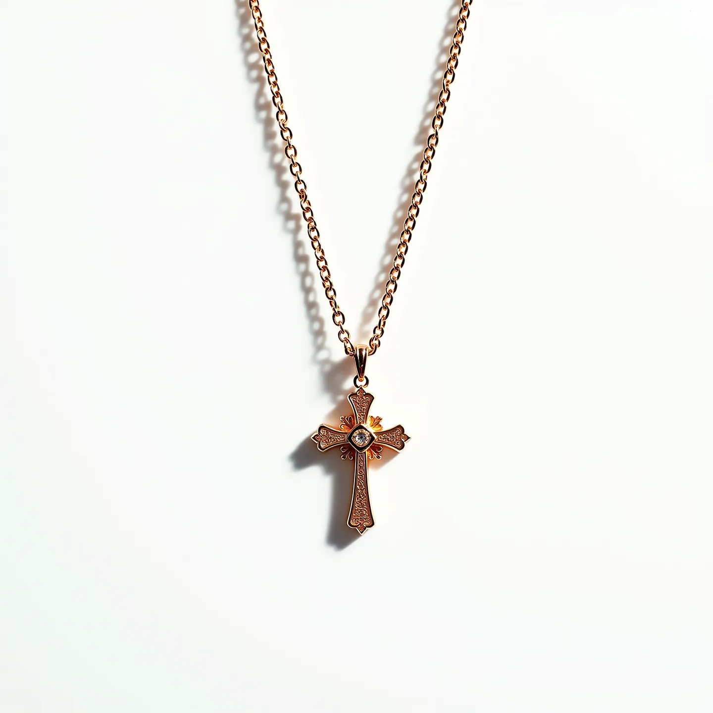 This gold cross necklace features intricate detailing and is crafted from a rich, gold-toned material. The cross itself has an ornate design, with carved patterns that enhance its elegance. At the center of the cross, there is a round, brilliant-cut gem set securely within a bezel setting, providing a focal point of sparkle. The necklace is suspended from a matching gold chain, which appears to be a cable chain style, offering both durability and classic appeal. The attachment to the chain is via a small, gold bail, which connects seamlessly to the top of the cross.