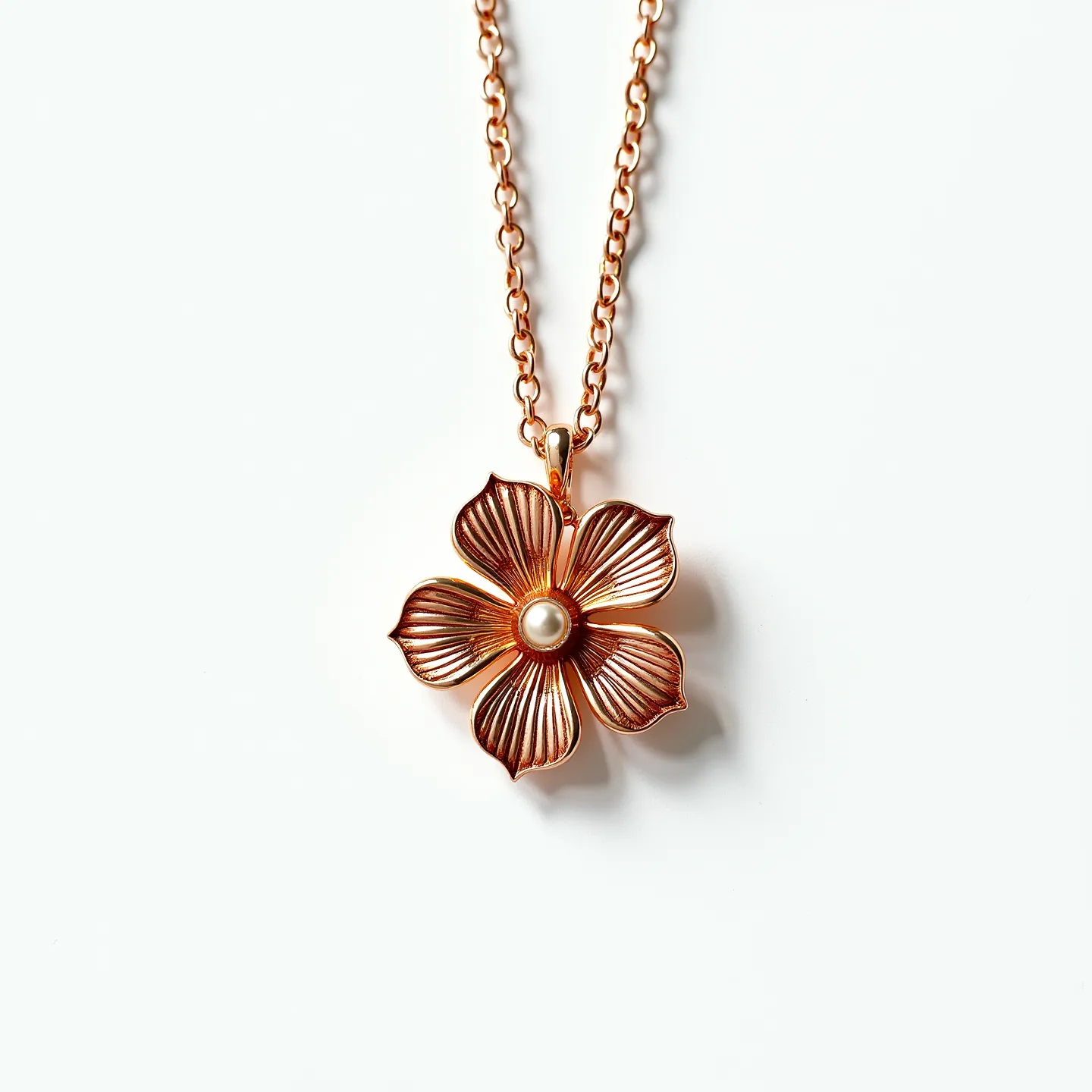 This gold flower necklace showcases an intricately designed floral pendant crafted in a warm gold-tone metal, featuring elegant, detailed petals radiating outward. At the center of the flower is a round, lustrous pearl, set smoothly to accentuate its sheen against the gold backdrop. The pendant hangs from a classic chain composed of uniform links, offering both durability and a timeless aesthetic. The necklace is completed with a secure clasp that ensures a comfortable fit while seamlessly integrating with the overall design.