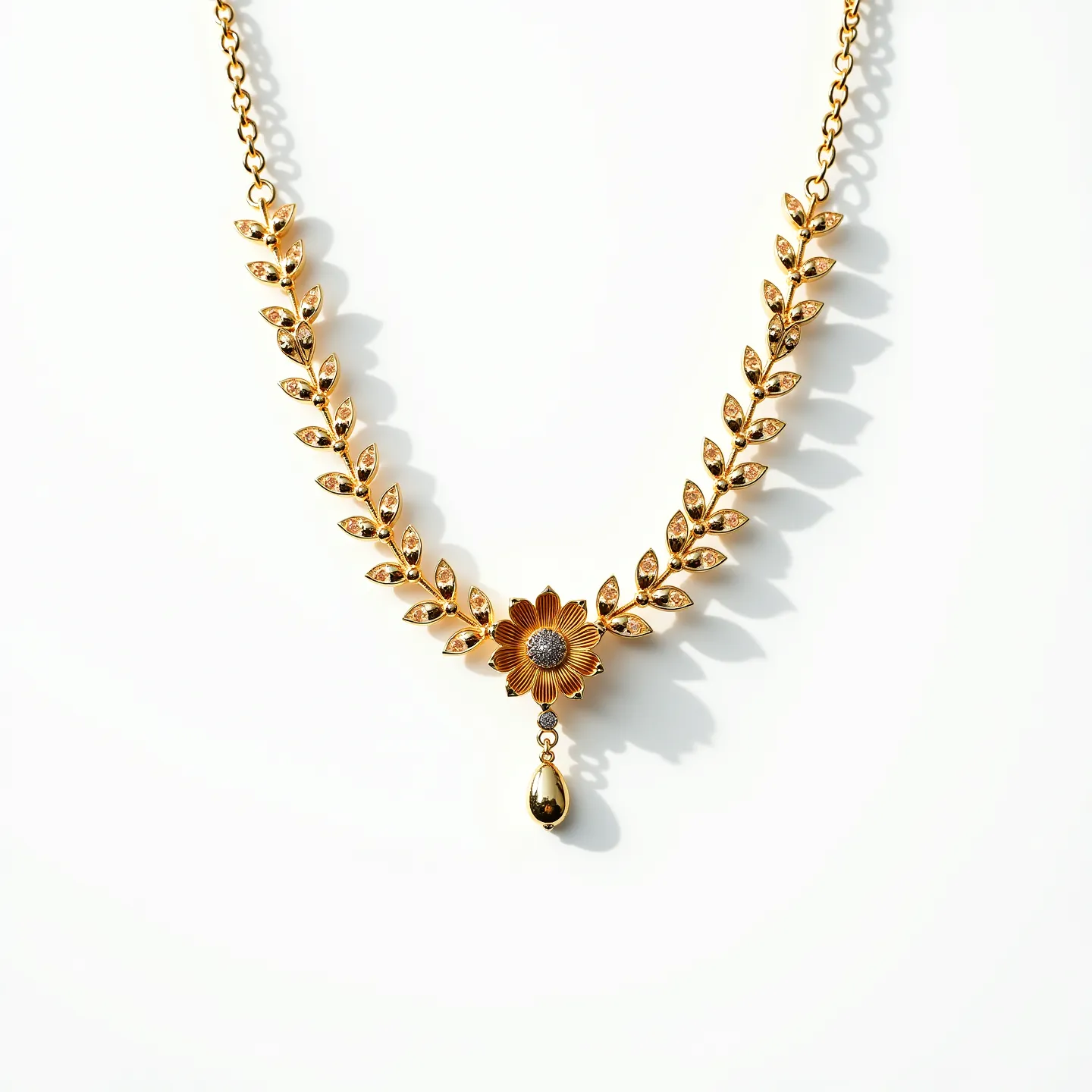 This gold flower necklace features an elegant design composed of intricately linked leaf motifs leading to a central floral element. The pendant is crafted with a delicate gold flower that highlights a textured, central component that may suggest the presence of smaller gems. Each leaf-like segment appears to be carefully sculpted, possibly with inset stones or detailed engravings, enhancing its ornate aesthetic. At the center of the flower, a small cluster of sparkling stones is visible, suggesting crystal or diamond embellishments set in a classic prong setting. Dangling from the flower is a teardrop-shaped embellishment, flawlessly polished and reflective, adding dynamic movement and elegance. The necklace is connected with a chain that seamlessly blends into its design elements, and the clasp is likely a standard lobster or spring ring, ensuring a secure and comfortable fit.