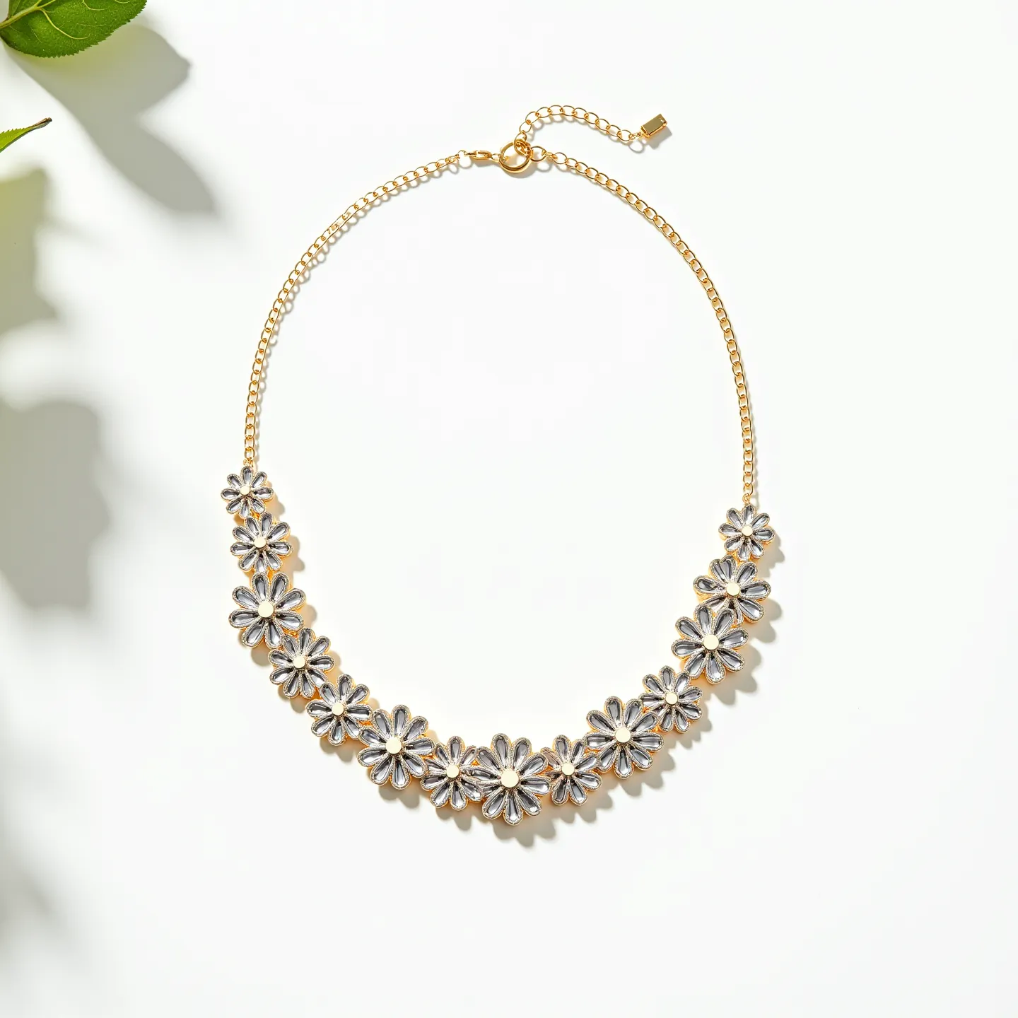 This gold flower necklace features a series of intricately designed flower motifs that are likely crafted from gold-plated metal, giving them a luxurious yet delicate appearance. The centers of these flowers appear to have small, clear stones, possibly resembling diamonds or cubic zirconia, which are round-cut and set seamlessly within each bloom, adding a subtle sparkle. The necklace is joined by a gold chain that completes the cohesive floral design. It is secured with a lobster clasp, accompanied by an adjustable extension chain, allowing for a customizable fit while maintaining elegance and functionality.