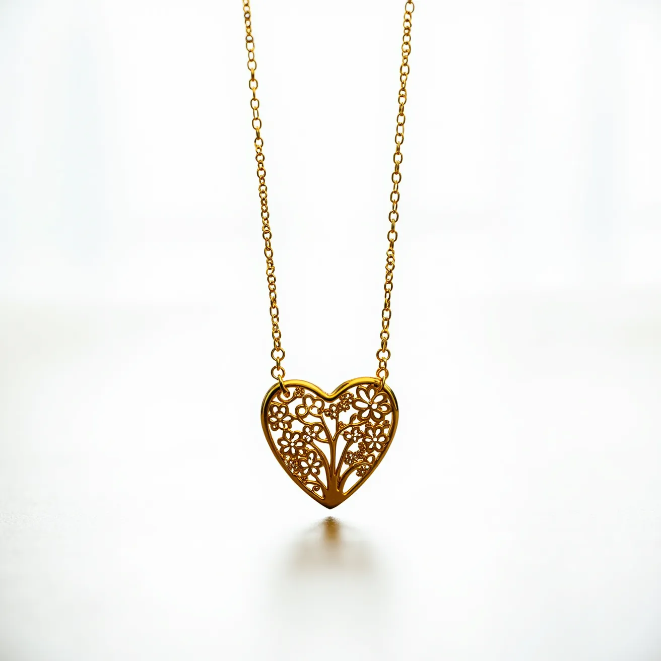 This gold heart necklace features a delicate chain that supports an intricately designed heart-shaped pendant. The pendant is crafted from gold and showcases an elaborate filigree pattern, with small floral motifs interwoven throughout. The careful craftsmanship highlights the openwork design, allowing light to pass through the intricate details. The necklace's chain is composed of interconnected links, providing a classic and elegant look. The overall design is cohesive and harmonious, emphasizing the artistic nature of the piece.