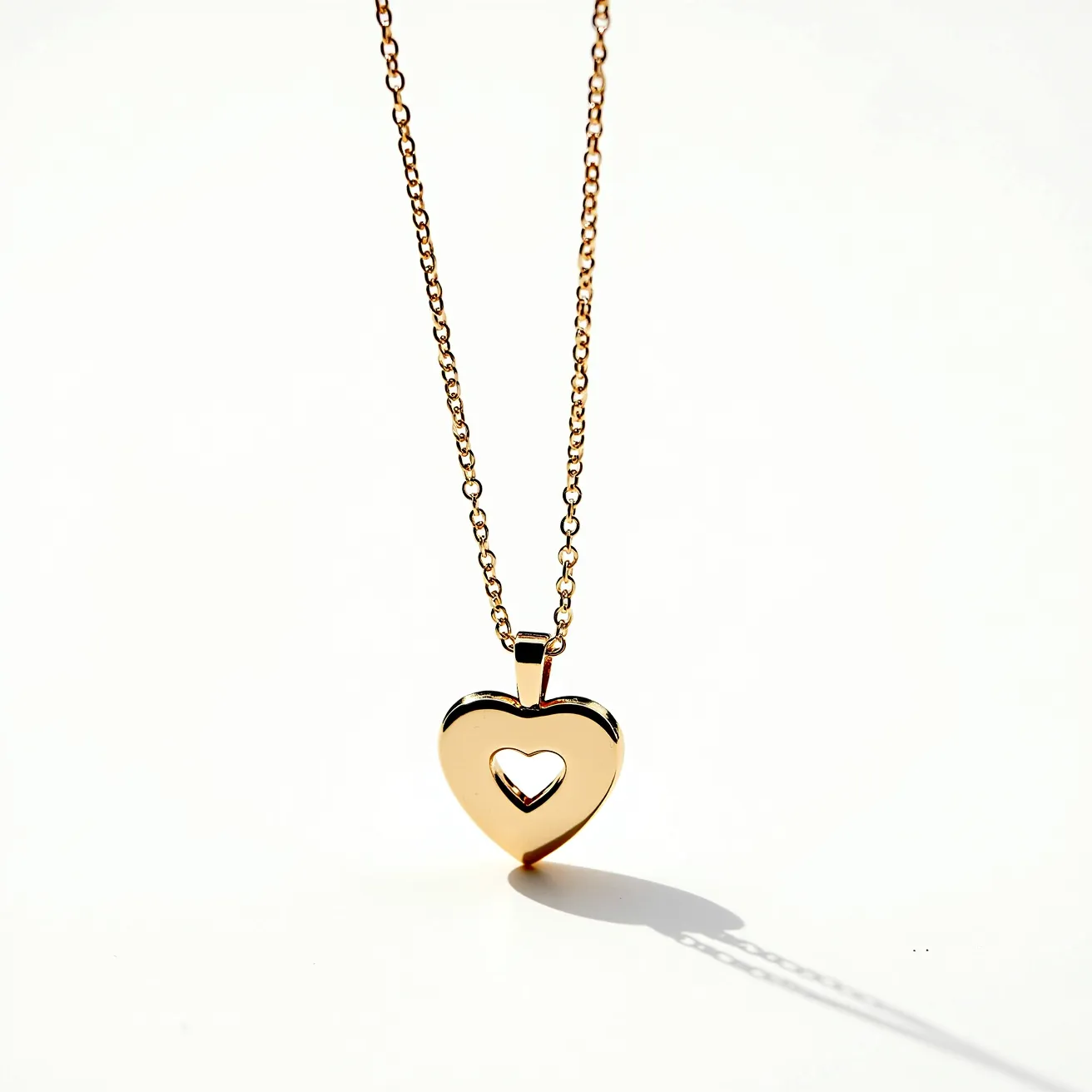 This gold heart necklace features a delicate chain made of gold, linking together seamlessly to form a classic, elegant piece. The pendant is a polished heart shape with an inner cut-out heart, crafted from gold to match the chain, creating a cohesive and stylish design. The pendant is attached to the chain through a bail that allows it to hang gracefully. The necklace likely includes a standard clasp, ensuring it can be securely fastened around the neck. The overall simplicity and craftsmanship highlight the luxurious nature of the materials used.