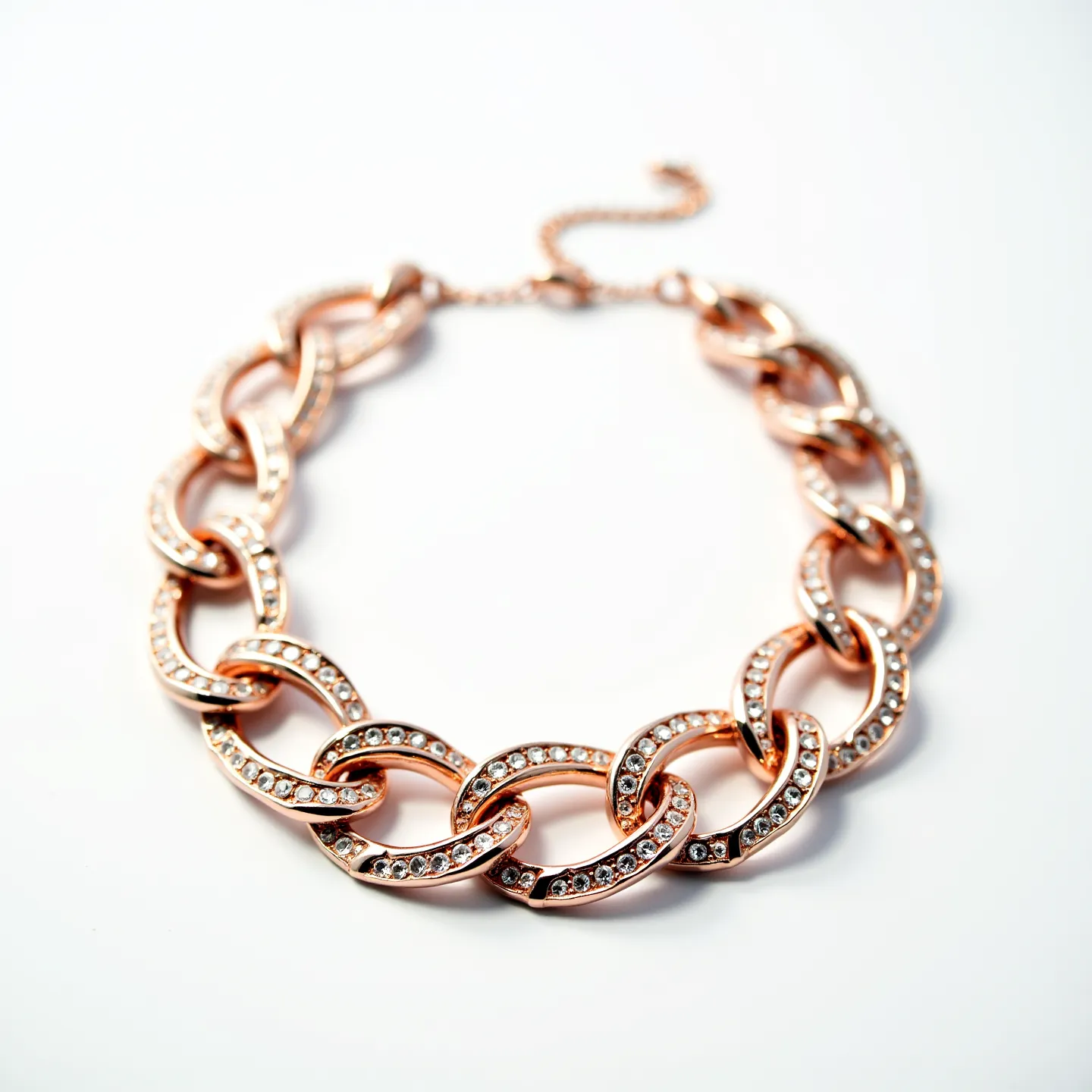 This gold link necklace showcases a series of interlocking rose gold links, each adorned with small, round-cut crystals that add a touch of sparkle. The crystals are set in a pavé style, enhancing the overall elegance of the piece. The necklace features a lobster clasp, providing a secure closure, and includes an adjustable chain extension for versatile length options. The harmonious blending of the warm tones of rose gold with the brilliance of the crystals gives this piece a luxurious and sophisticated appearance.