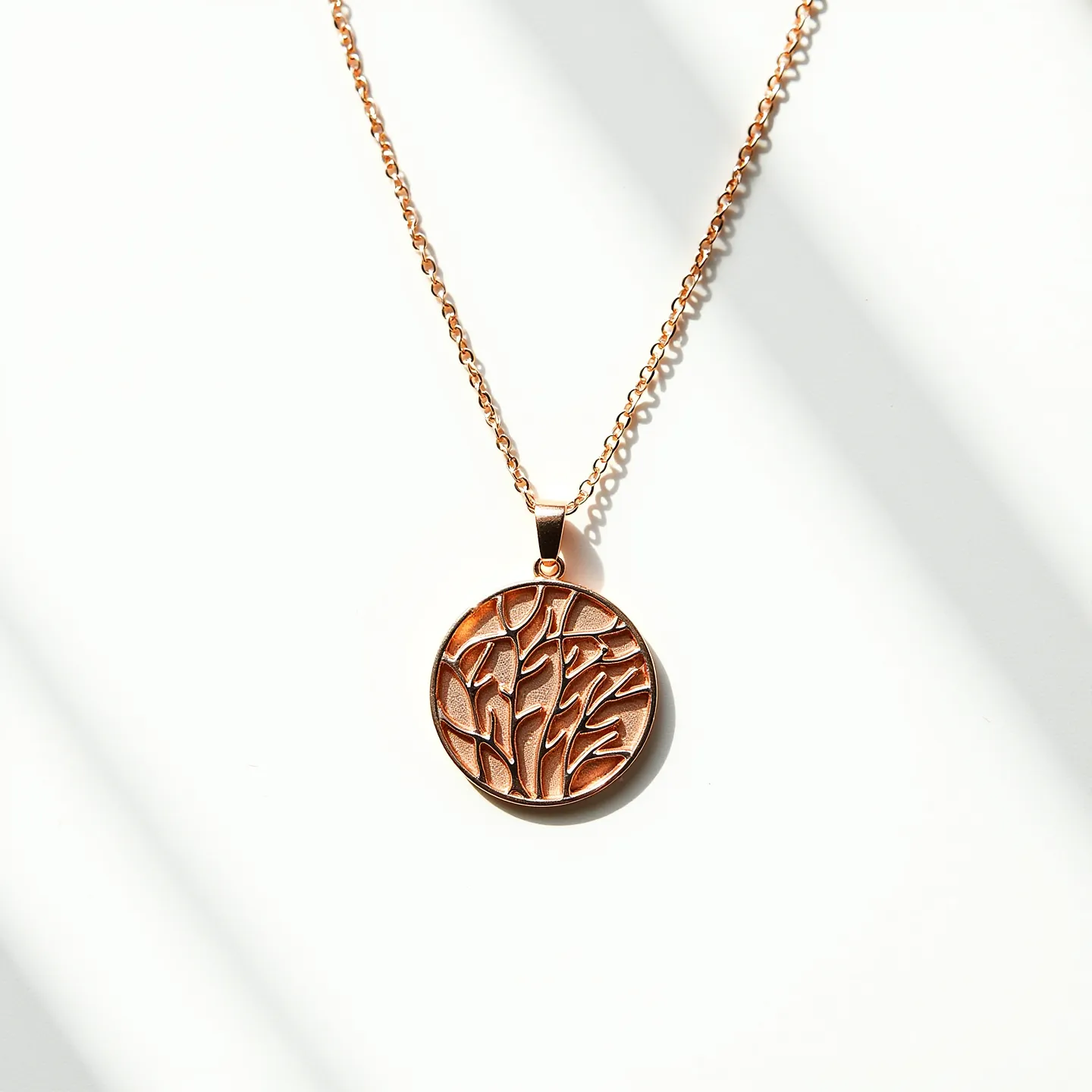 This gold medallion necklace features a polished round pendant with an intricate abstract design, possibly inspired by nature or geometric elements, crafted from a rich golden metal. The chain is composed of uniformly sized oval links, offering a delicate yet sturdy appearance, likely made from the same gold material as the medallion, giving it a cohesive and luxurious look. The pendant is attached to the chain with a simple gold bail that allows for movement and ensures the medallion hangs correctly. The necklace is completed with a classic lobster clasp, providing a secure and functional closure.