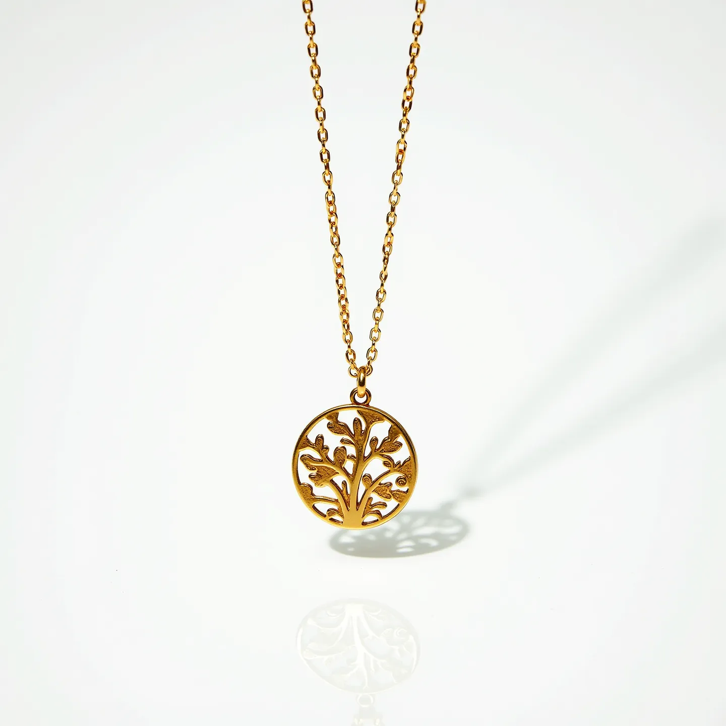 This gold medallion necklace features a delicate chain crafted from polished gold links, supporting a circular pendant with an intricate cut-out design resembling a stylized tree. The medallion itself exhibits both artistic detail and a smooth finish, enhancing its elegant appearance. The chain is equipped with a simple and unobtrusive clasp that ensures secure and comfortable wear. The design emphasizes artistry without the accompaniment of any gemstones, highlighting the craftsmanship of the gold elements.