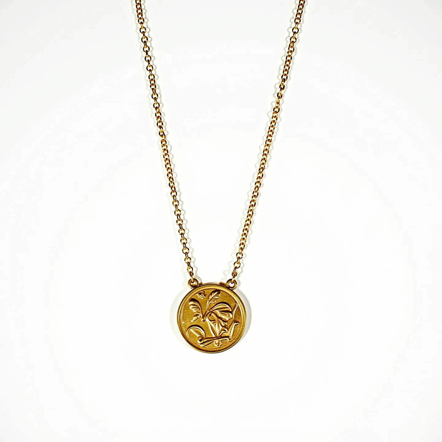 This gold medallion necklace features a round pendant crafted from gold, with an intricately engraved botanical design on its surface, showcasing exquisite detailing. The medallion is suspended from a fine gold chain, which appears to be of a cable link design, complementing the elegant simplicity of the pendant. The necklace includes a jump ring or bail attachment that connects the pendant to the chain, ensuring a seamless integration. Its craftsmanship highlights both functionality and aesthetic appeal, perfect for adding a touch of sophistication to any ensemble.