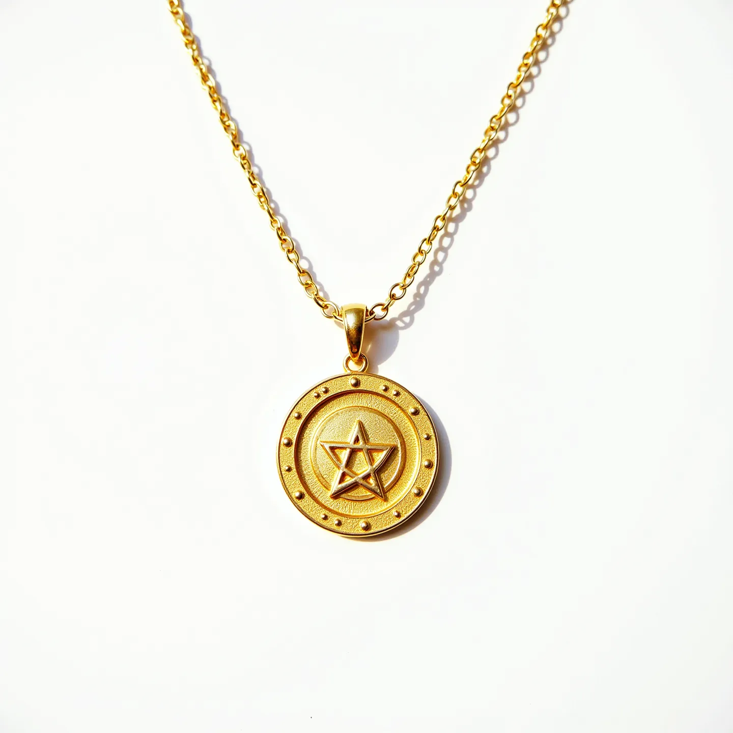 This gold medallion necklace features a round pendant crafted from polished gold, embellished with a raised design of a five-pointed star encircled by a dotted border. The medallion hangs from a classic gold chain, which is composed of interconnected links providing a smooth and elegant drape. The pendant is attached to the chain via a sturdy loop bail, allowing for easy movement and a secure connection. This necklace embodies a minimalist yet symbolic aesthetic, making it versatile for everyday wear or special occasions.