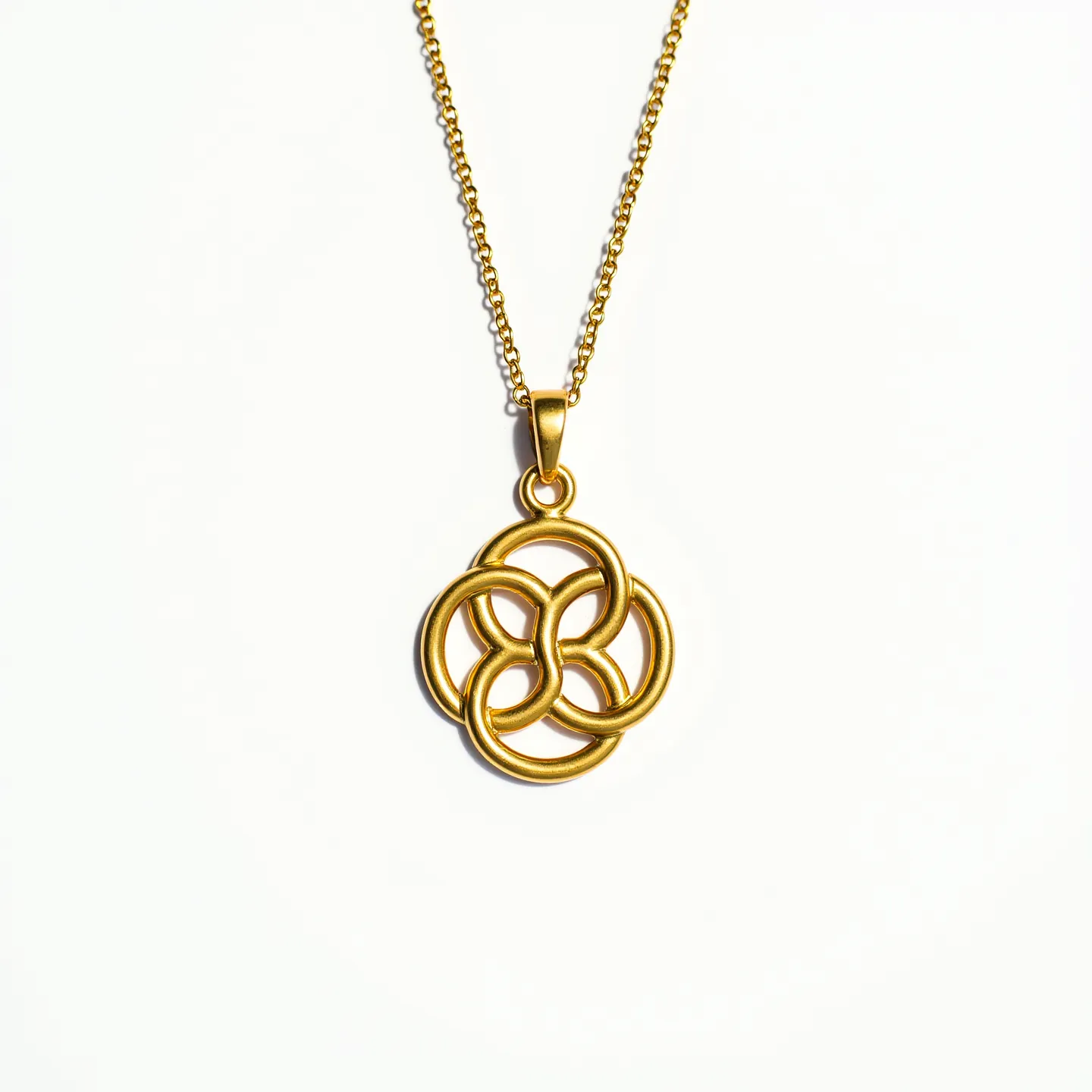 This gold medallion necklace features an intricate design composed of interlocking circular patterns. It appears to be crafted from gold, giving it a polished and luxurious look. The medallion is suspended from a chain that is also gold, composed of small, closely linked round pieces, providing a classic yet modern aesthetic. There are no visible gems or stones incorporated into the design, and the entire piece maintains a uniform golden hue. The necklace includes a simple, elegant bail through which the chain runs, ensuring the medallion hangs securely.