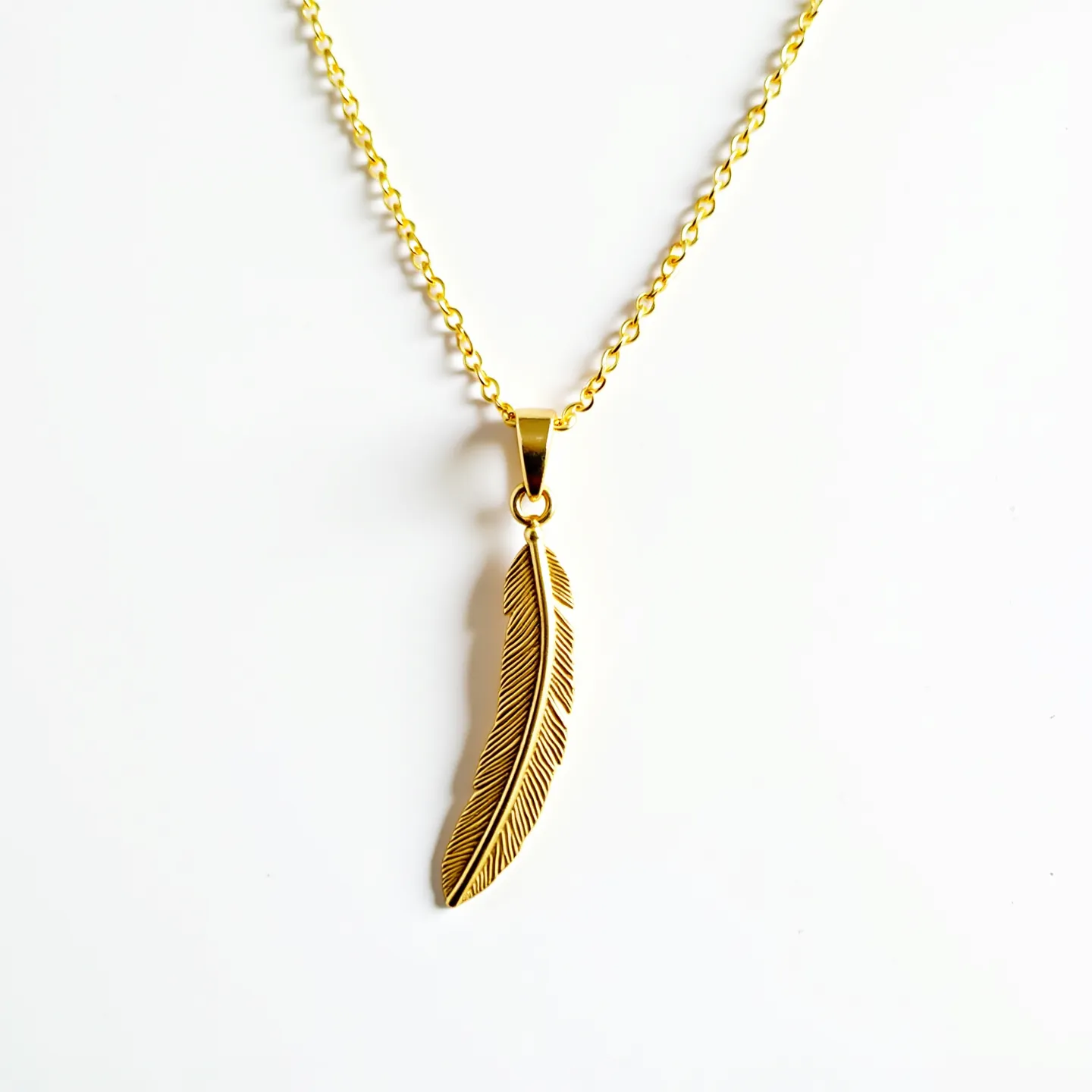 This gold necklace features a delicate chain crafted from what appears to be polished gold links, creating a classic and elegant appearance. Suspended from the chain is a pendant shaped like a feather, intricately designed with fine detailing to mimic the natural texture of a feather. The pendant is attached to the chain with a simple gold bail, allowing it to hang freely, adding a touch of sophistication to the overall design. The necklace is likely equipped with a standard lobster clasp, providing a secure yet easy-to-use closure.