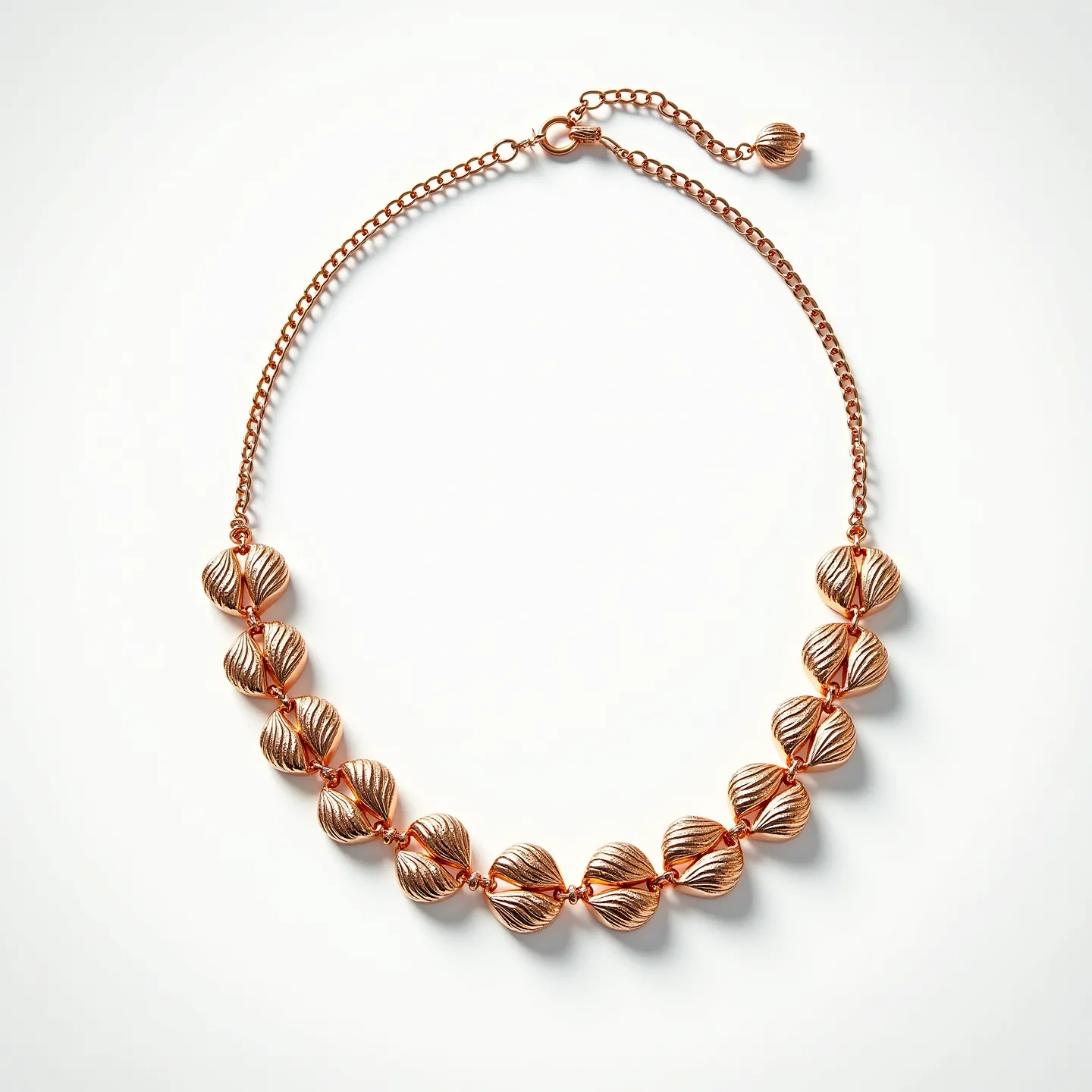 This gold necklace features a series of beautifully crafted gold beads, each with a distinct ribbed texture that resembles a shell or leaf design. The beads are connected by small gold links, enhancing the necklace’s fluidity and elegance. It is equipped with a lobster clasp, allowing for secure attachment, along with a short extension chain that ends with a single matching bead, providing adjustable length. The cohesive and luxurious look of the necklace is highlighted by the reflective quality of the polished gold surface, making it an eye-catching piece of jewelry.