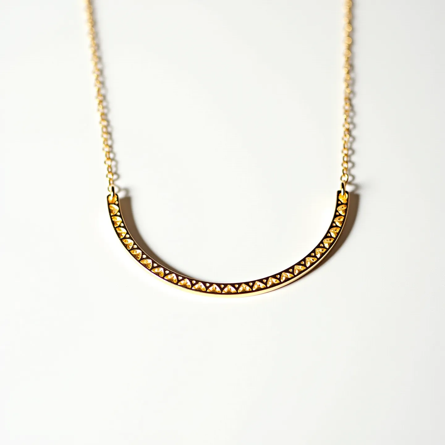 This gold necklace features a delicate chain that supports a semi-circular pendant. The pendant is adorned with small, pyramid-shaped gold studs that are uniformly set along its curved surface, giving it a textured and intricate design. The chain appears fine and lightweight, designed to complement the elegance of the pendant. The necklace is likely secured with a simple clasp mechanism, though the specific type is not visible. The overall design strikes a balance between modern simplicity and decorative detail, making it suitable for a variety of occasions.