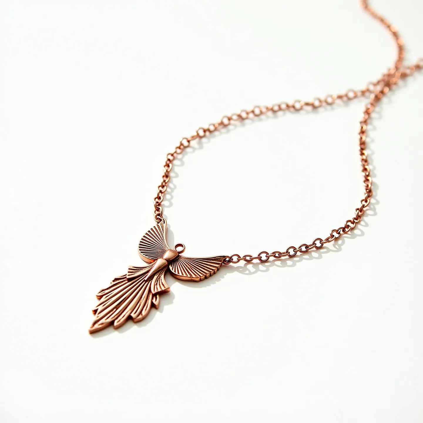 This gold necklace features a beautifully crafted chain with a distinctive pendant, which resembles an intricately designed leaf or feather with fine grooves that enhance its texture and detail. The necklace appears to be made of rose gold, lending it a warm and elegant hue. The chain consists of interlinked oval links that form a classic and sophisticated look, complementing the pendant's intricate design. The necklace is likely secured with a clasp, typical of such designs, ensuring a secure fit while maintaining a seamless appearance. The overall aesthetic of the necklace is both elegant and artistic, making it a striking piece of jewelry suitable for various occasions.