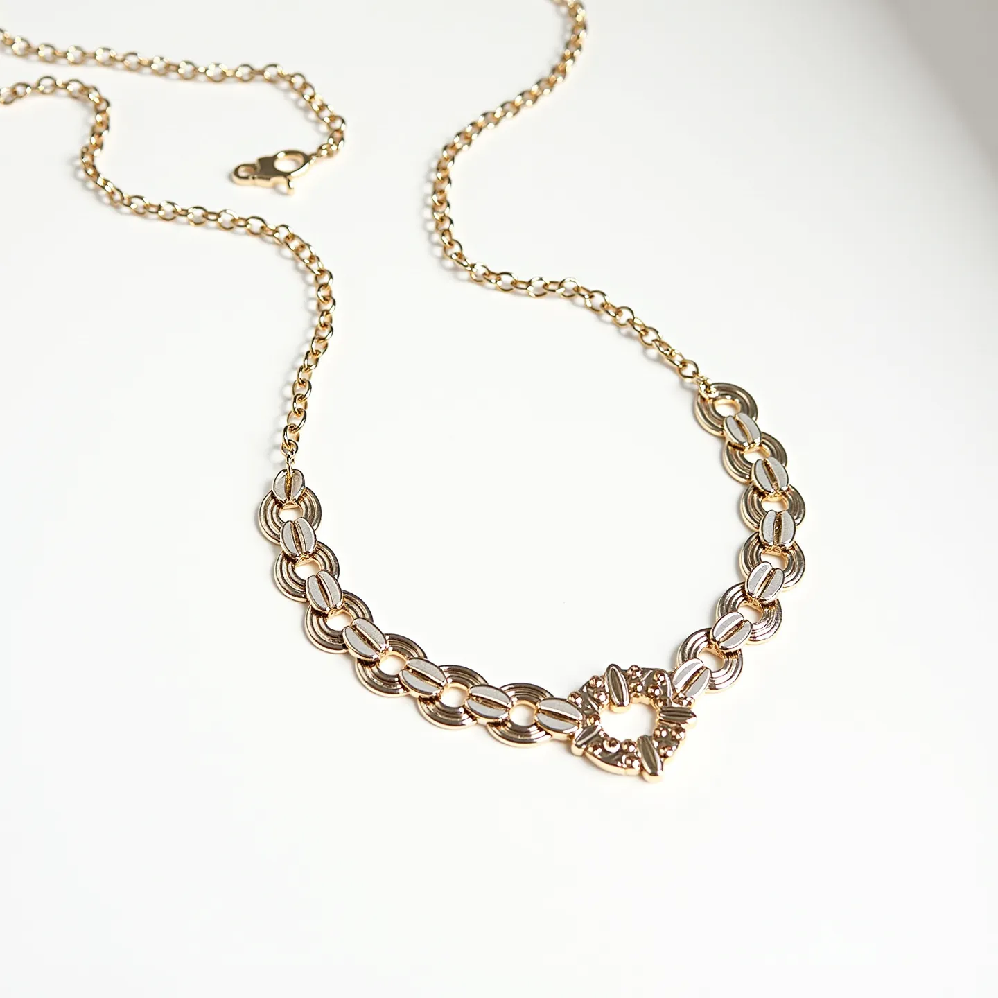 These gold necklace women feature a stunning design crafted from interlocking gold links arranged in a polished, elegant chain. The necklace showcases a circular motif at the center, adorned with small, sparkling stones that catch the light beautifully. Each link is carefully crafted to ensure a seamless appearance and a comfortable wear. The piece is completed with a secure lobster clasp, providing both functionality and a touch of sophistication. The harmonious blend of materials and design elements makes this necklace a versatile and timeless accessory.
