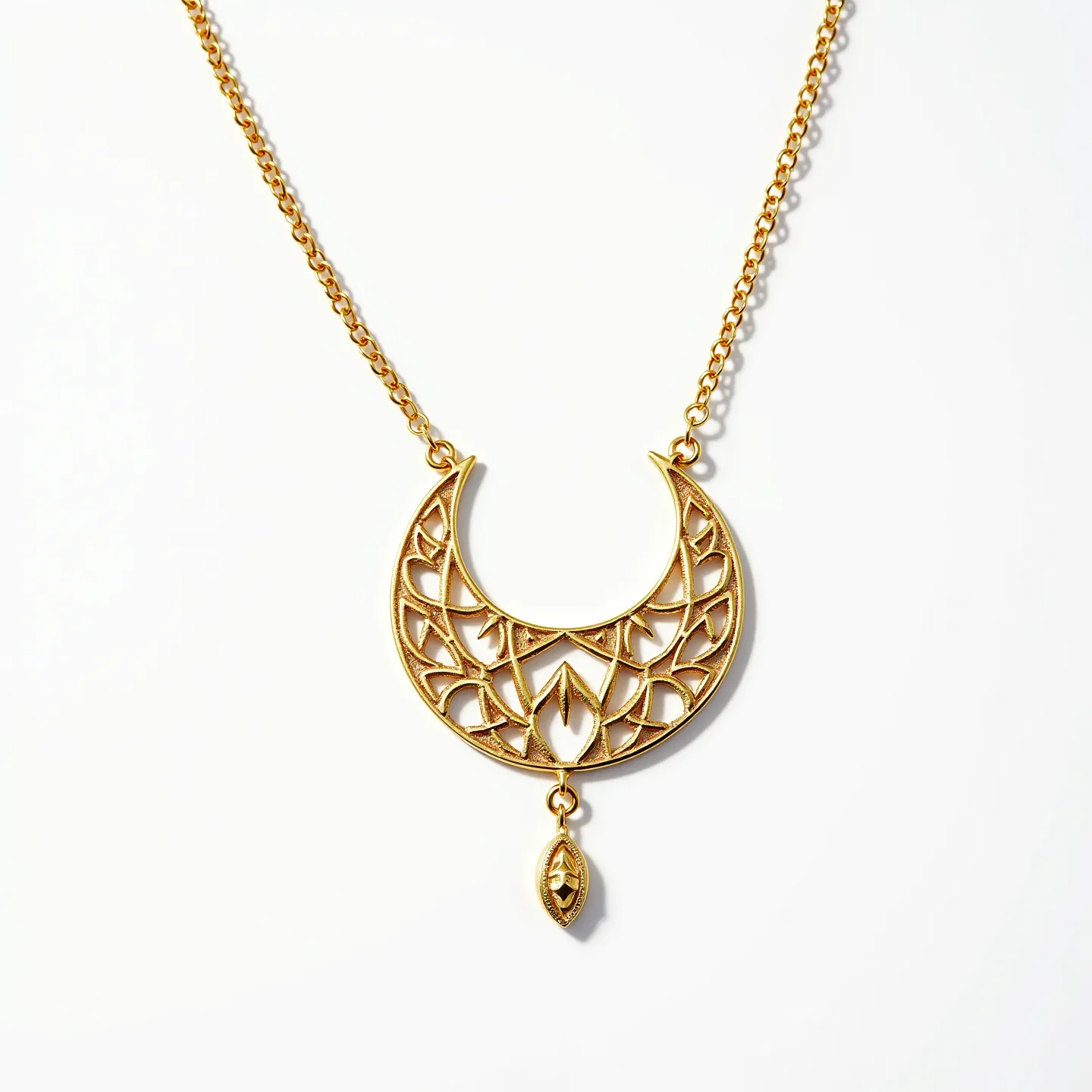 This gold necklace features an intricate openwork design in a crescent shape, crafted from what appears to be polished gold. The pendant includes a symmetrical pattern with lattice-like details, lending an elegant and refined appearance. Hanging from the center of the crescent is a small, teardrop-shaped charm that echoes the design motifs of the main pendant. The necklace is connected with a delicate gold chain that enhances its overall gracefulness.