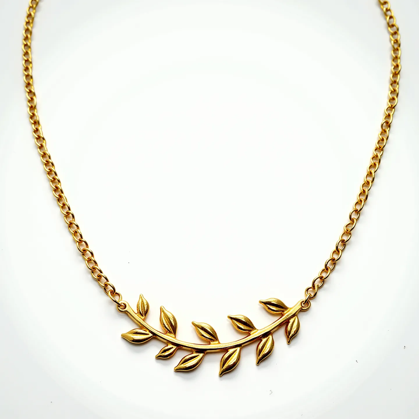 This gold necklace is adorned with a delicate chain and features a central motif designed to resemble a branch with leaves. The necklace's main material appears to be gold, which gives it a luxurious and elegant finish. There are no visible gemstones attached, focusing instead on the smooth, polished gold of the leaves and branch. The necklace is likely secured with a standard clasp, ensuring ease of wear and a secure fit. The overall design combines simplicity and sophistication, making it a versatile accessory for various occasions.