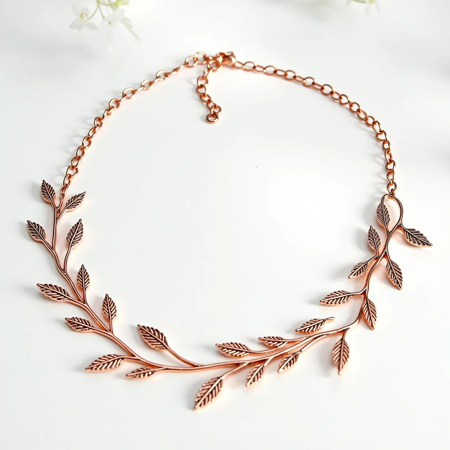 This gold necklace features an elegant design inspired by nature, with intricately crafted leaf motifs that form a delicate vine-like pattern. The material likely consists of gold or a gold-colored metal, adding to its sophistication and visual appeal. The leaves are uniformly arranged along the length of the necklace, emphasizing the organic aesthetics. It is connected by a chain with a series of circular links, allowing for an adjustable length, and culminates in a simple clasp that secures the necklace in place around the wearer’s neck. The craftsmanship highlights the fine details of each leaf, making it a standout piece for various occasions.