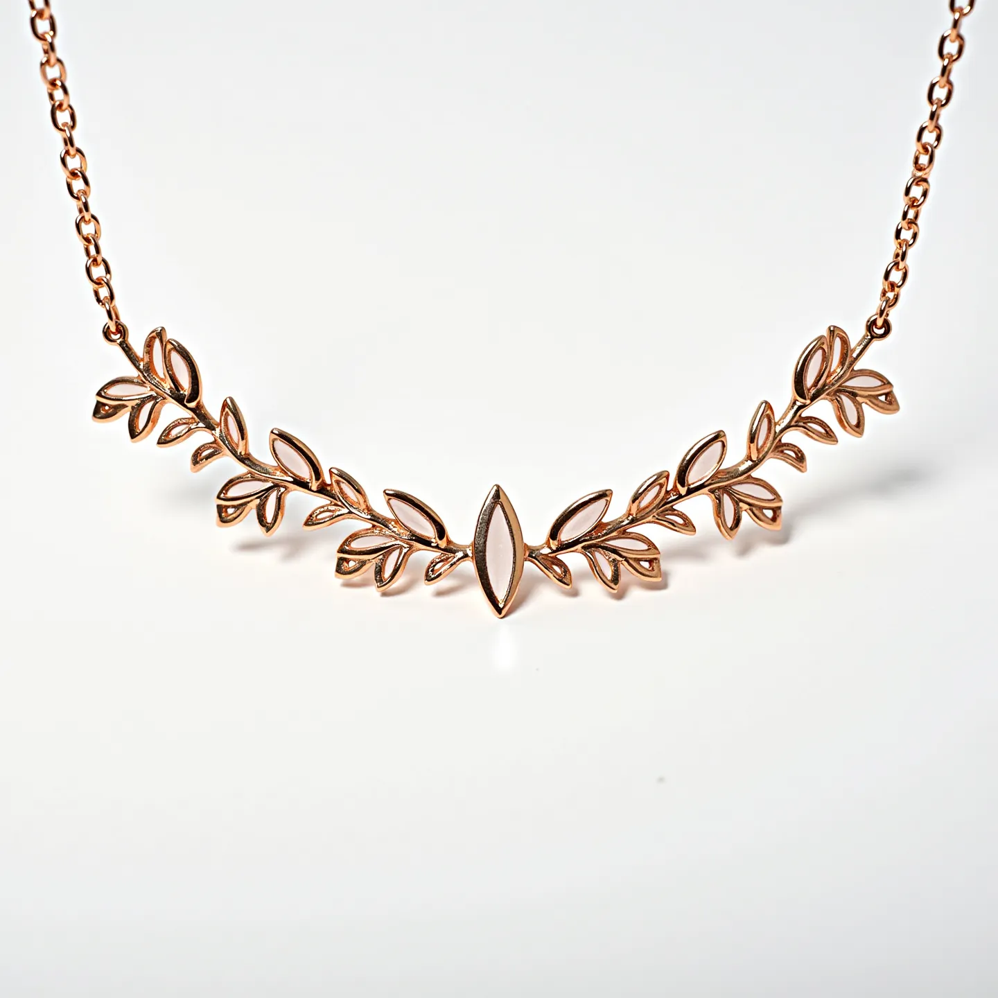 This gold necklace features a delicate design inspired by nature, with a series of leaf motifs intricately crafted from gold. The central focus is a marquise-shaped element, reminiscent of a single leaf or bud, surrounded by smaller, elegantly articulated leaves extending outward. The design suggests a sense of symmetry and balance, evoking a natural and organic aesthetic. The necklace appears to have a fine chain, adding to its elegant simplicity. There are no visible gems or stones, emphasizing the gold craftsmanship in the piece. The necklace likely secures with a standard clasp, typical of fine jewelry.