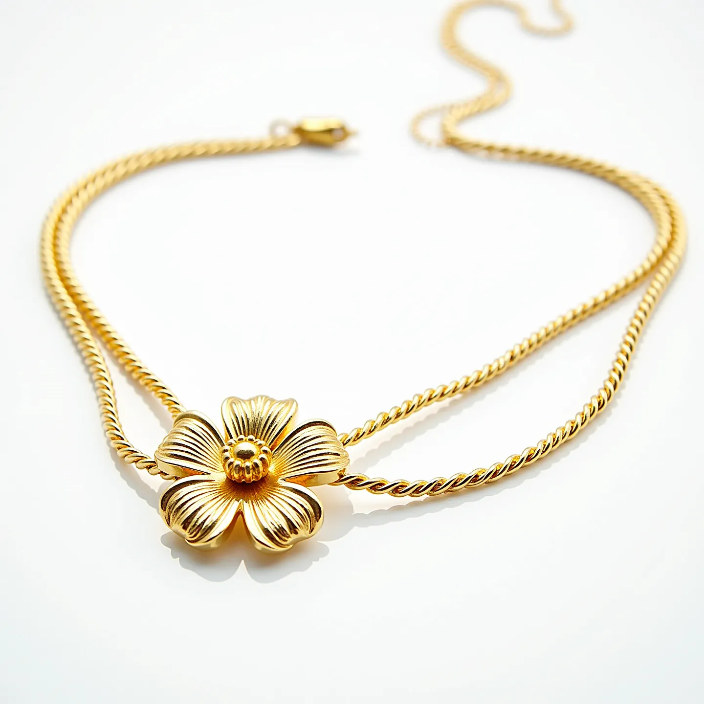 This gold rope necklace features a beautifully crafted floral centerpiece, adding a touch of elegance and artistry. The necklace is made from polished gold with intricately twisted strands, creating a classic rope design. The centerpiece is shaped like a flower, showcasing detailed petal engravings that enhance its visual appeal. The necklace is secured with a lobster clasp, ensuring both functionality and style. The overall design combines sophistication with a touch of nature-inspired charm, making it a versatile piece for various occasions.